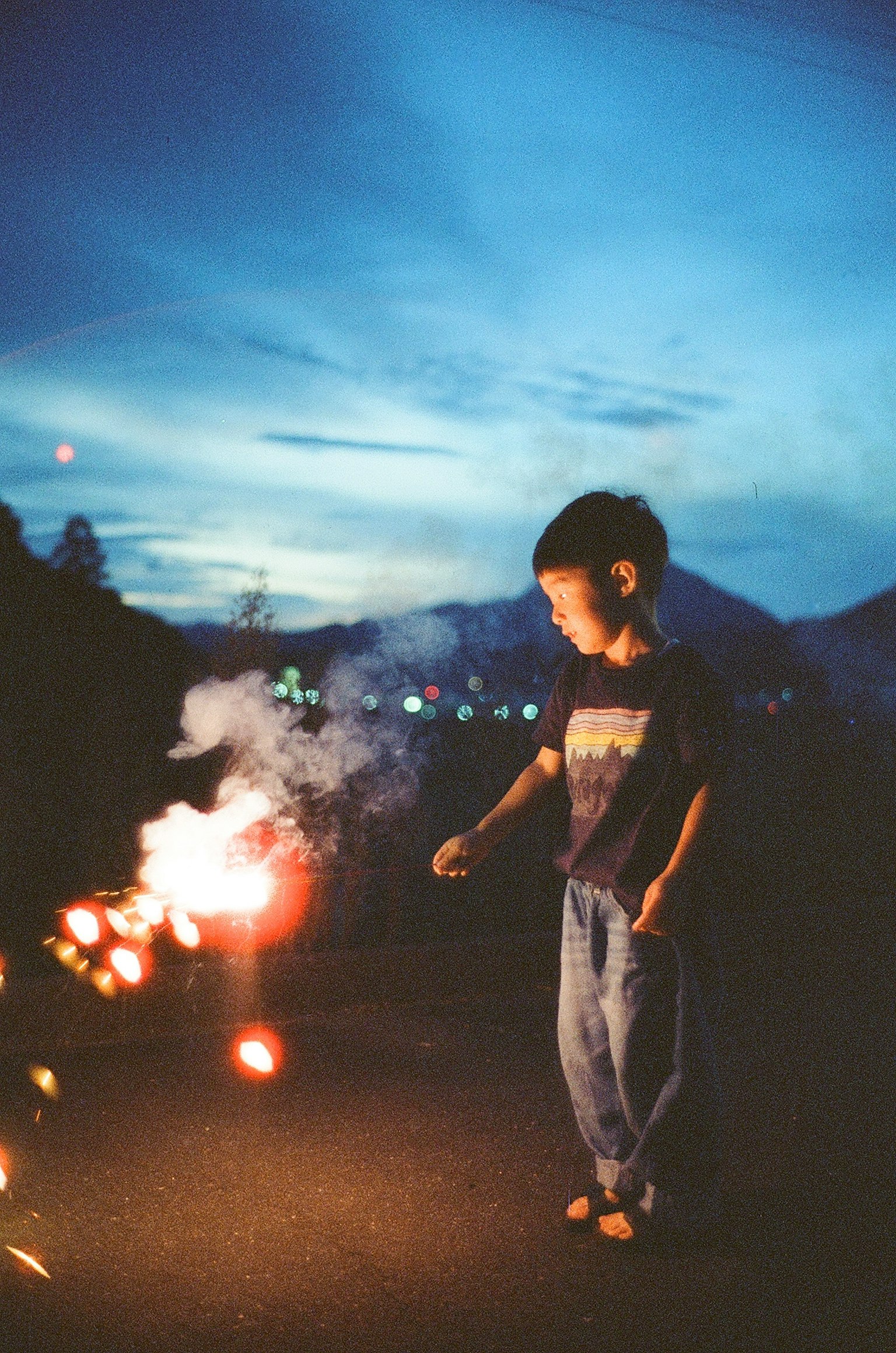 Silhouette of a child holding a sparkler under the night sky