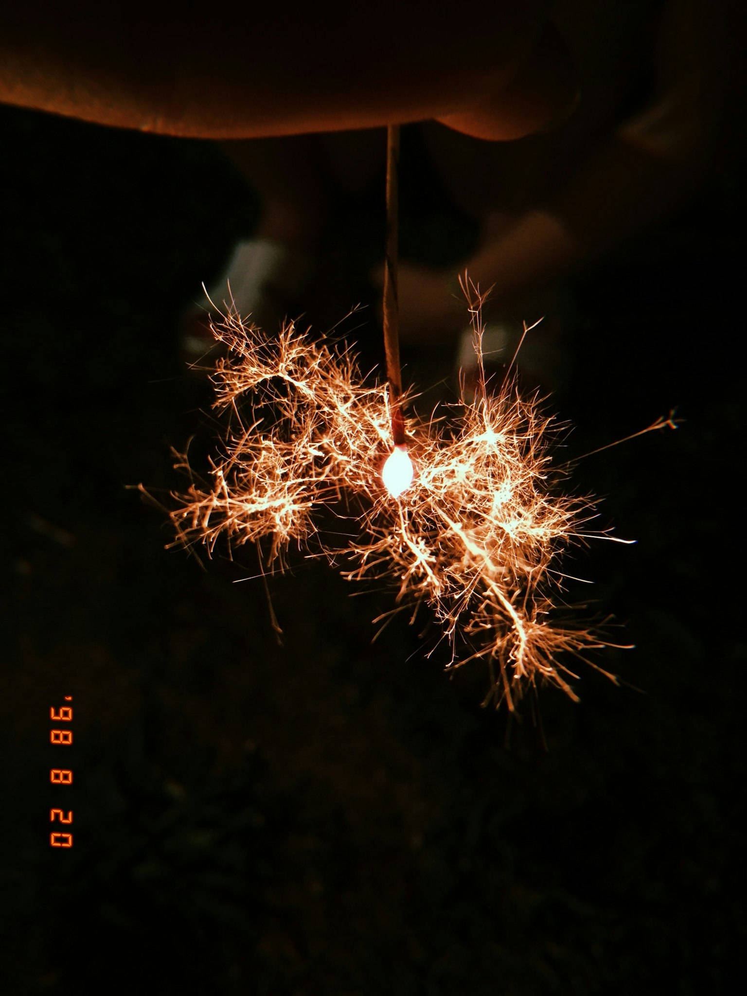 Hand hält ein Sprühfeuerwerk, das helle Funken erzeugt