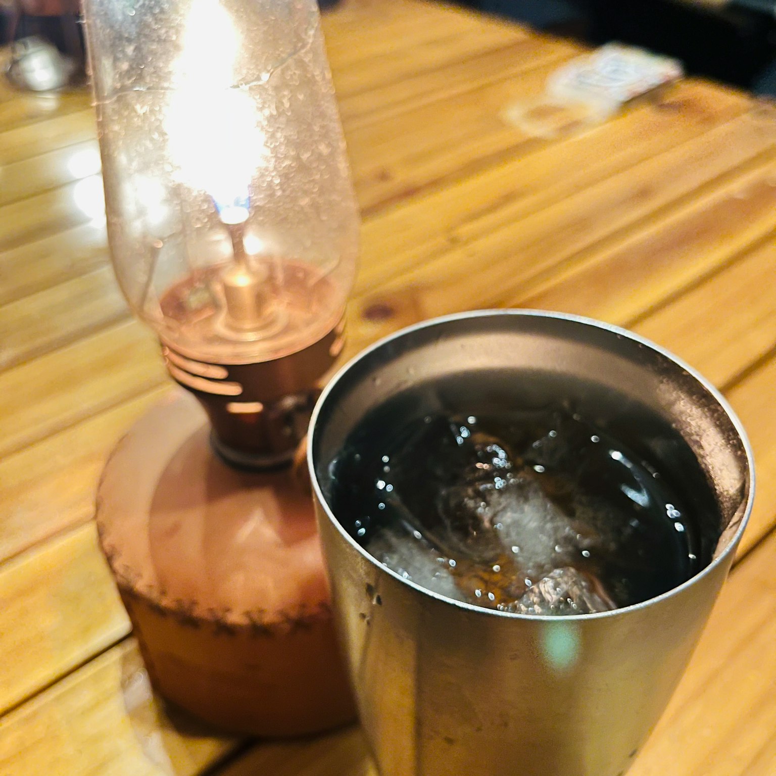 빈티지 오일 램프와 얼음이 담긴 금속 컵이 함께 있는 테이블