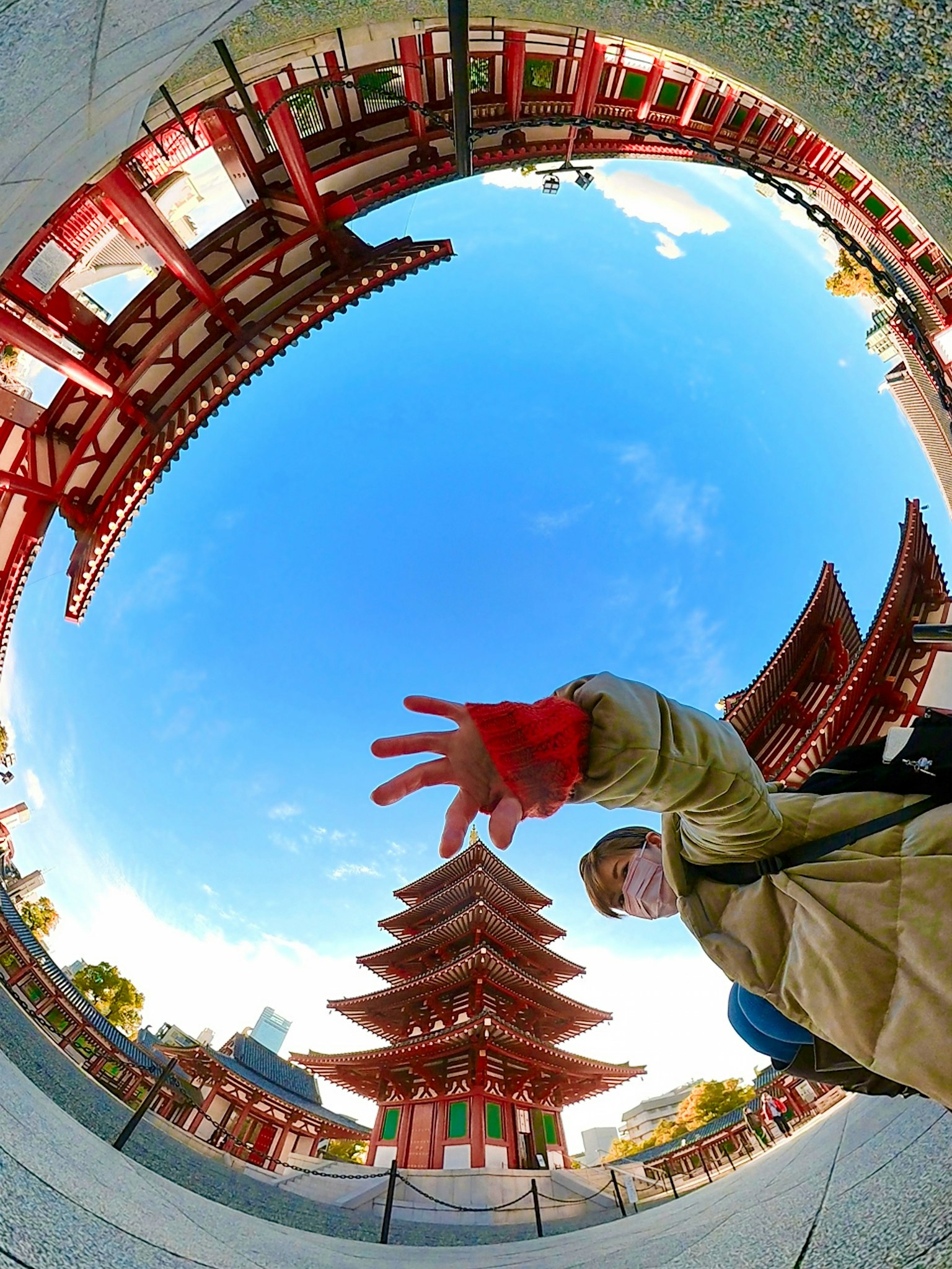 Personne montrant une pagode sous un ciel bleu avec des bâtiments rouges