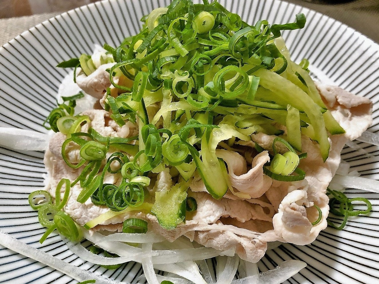 刻みねぎと豚しゃぶ風の具材がのった和風サラダの盛り付け