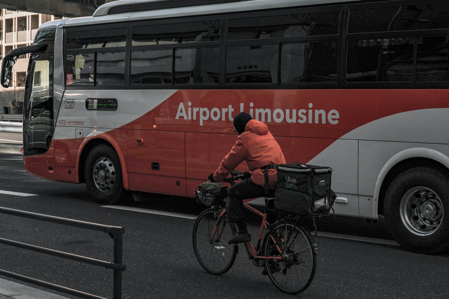 Image of an Airport Limousine bus alongside a cyclist in an orange jacket