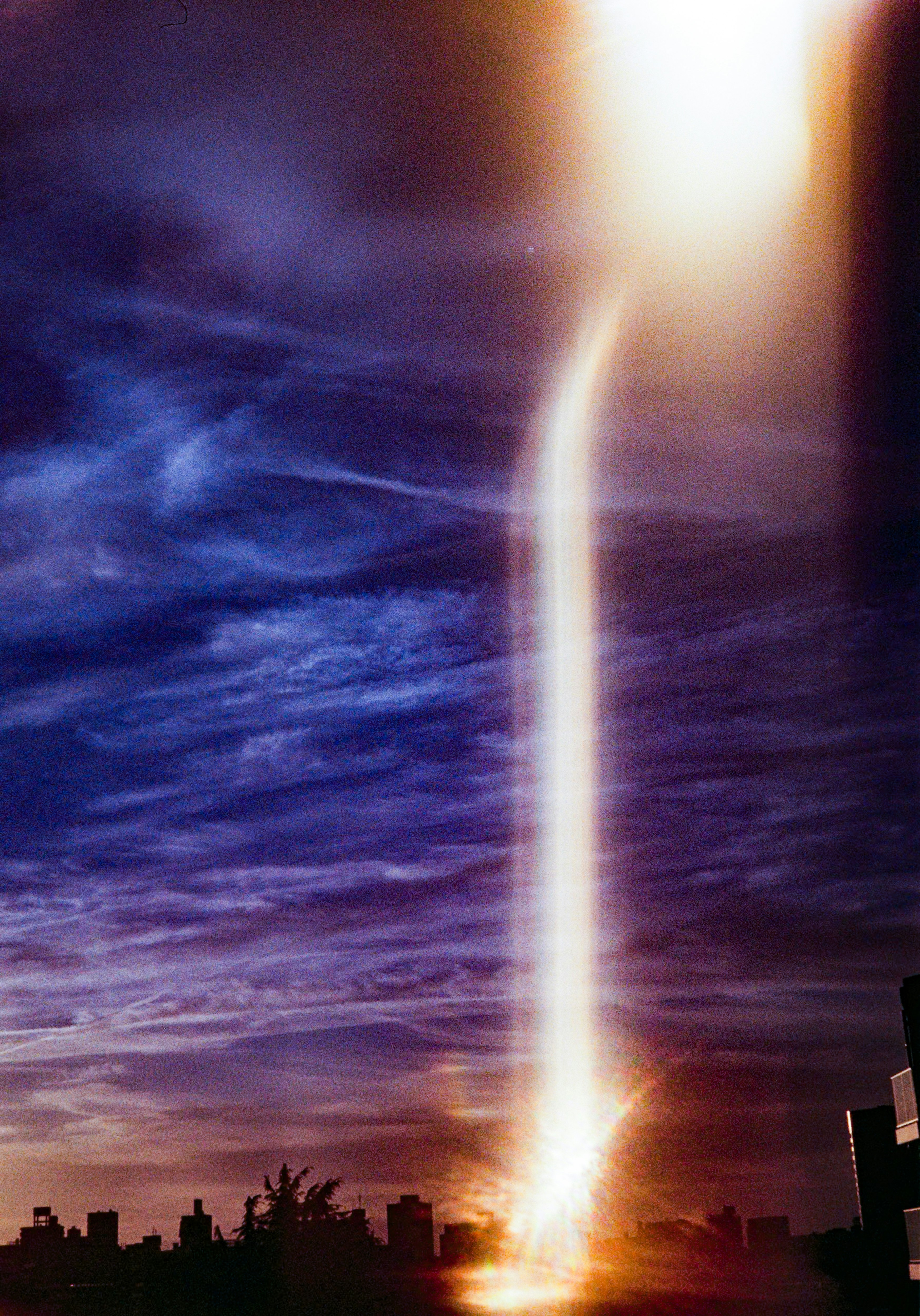 夕暮れの街並みを貫く光のビーム