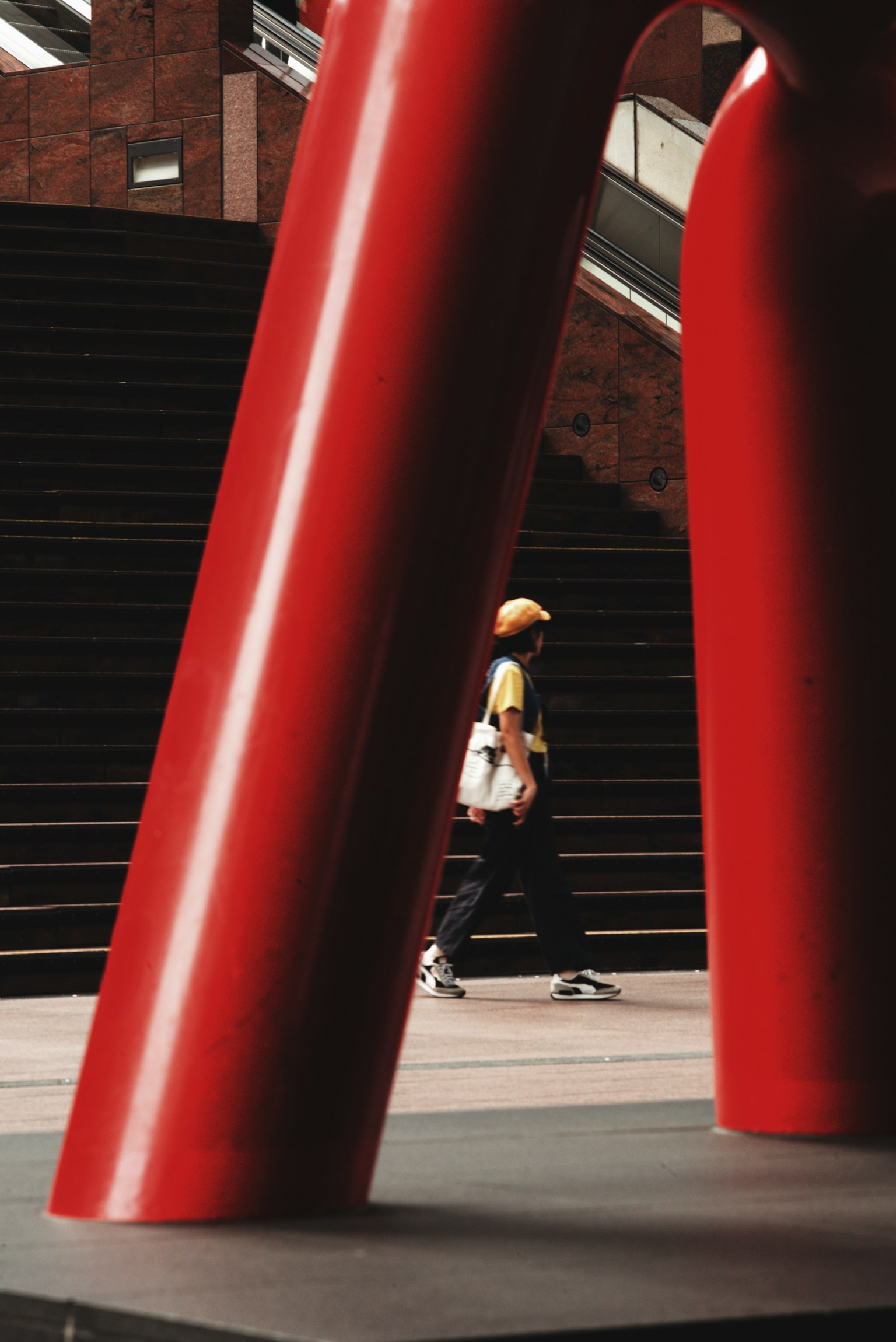 Eine Person, die unter den großen roten Beinen einer Skulptur geht