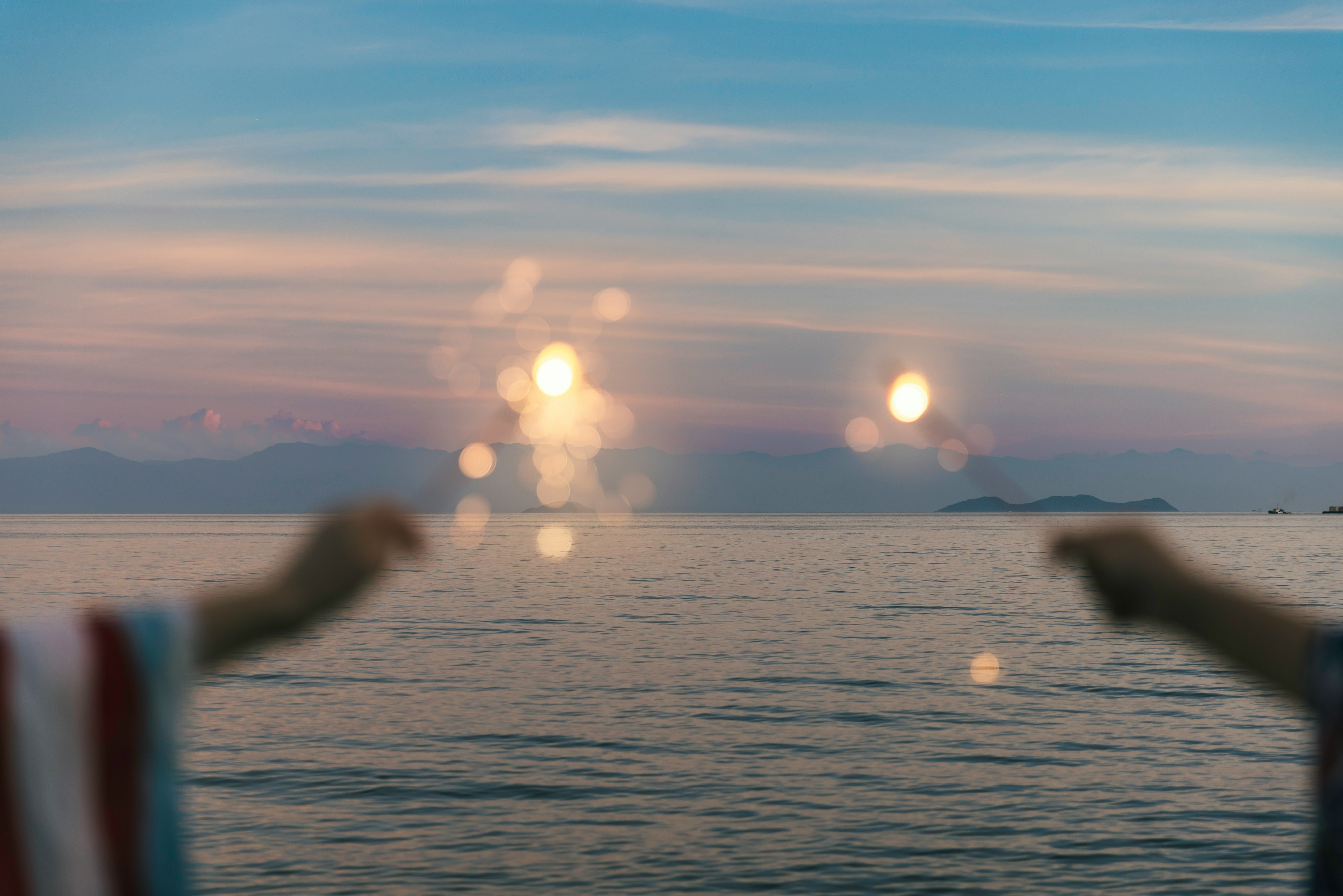 水平線に沈む夕陽の海と光のきらめき
