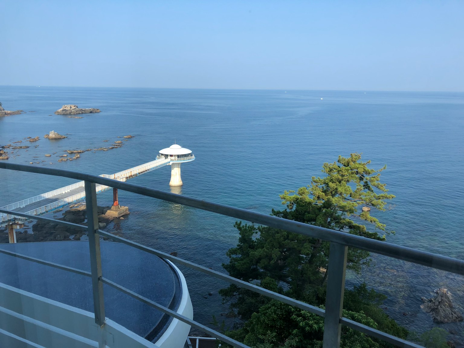 阳台上俯瞰蓝色海洋和天空的景色，有一个码头