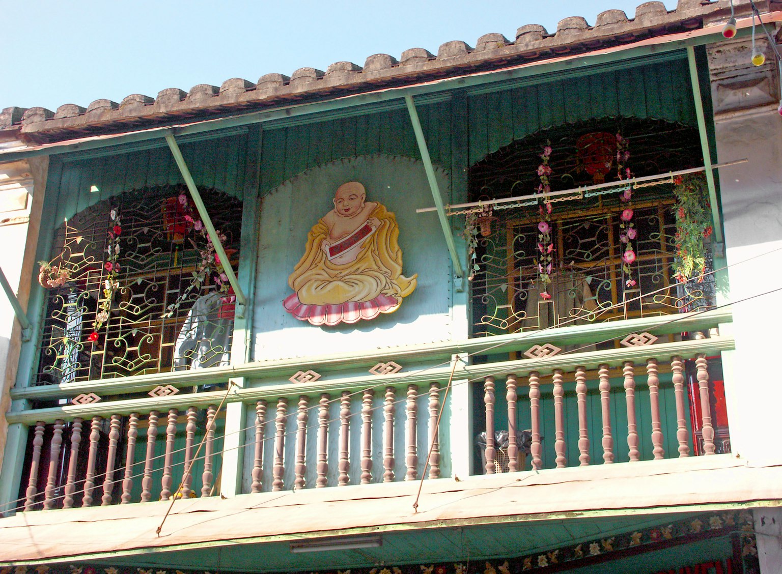 Edificio tradizionale con un balcone decorativo e un murale di Buddha