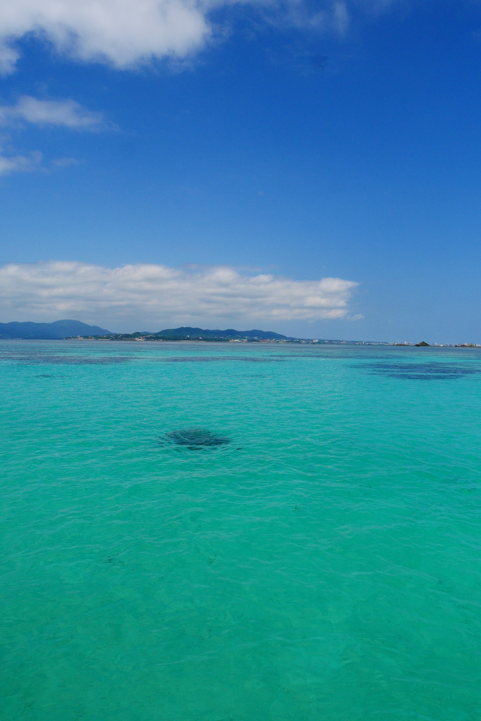 Mer émeraude claire avec ciel bleu et îles lointaines