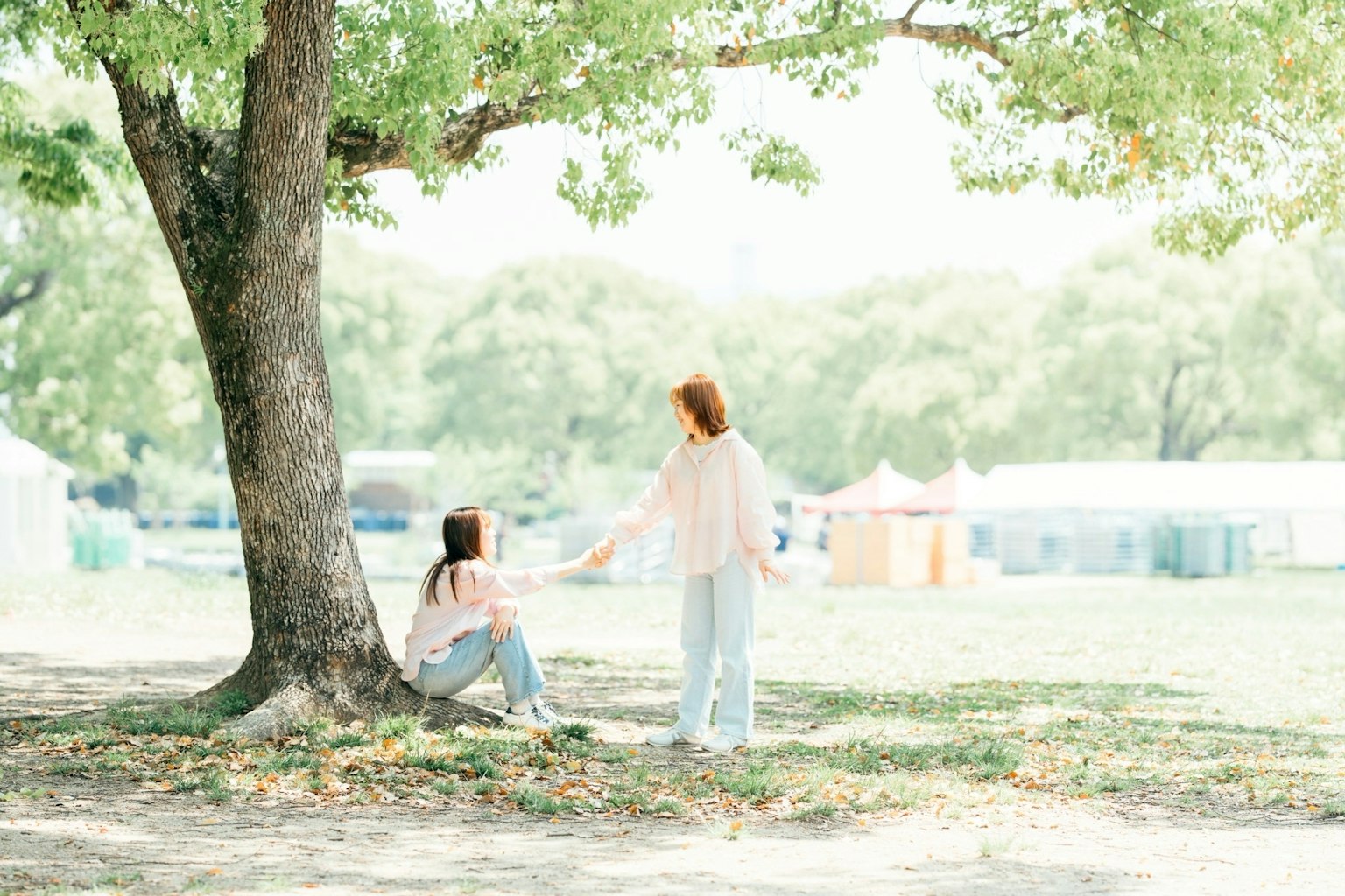 Dos mujeres interactuando bajo un árbol en un parque