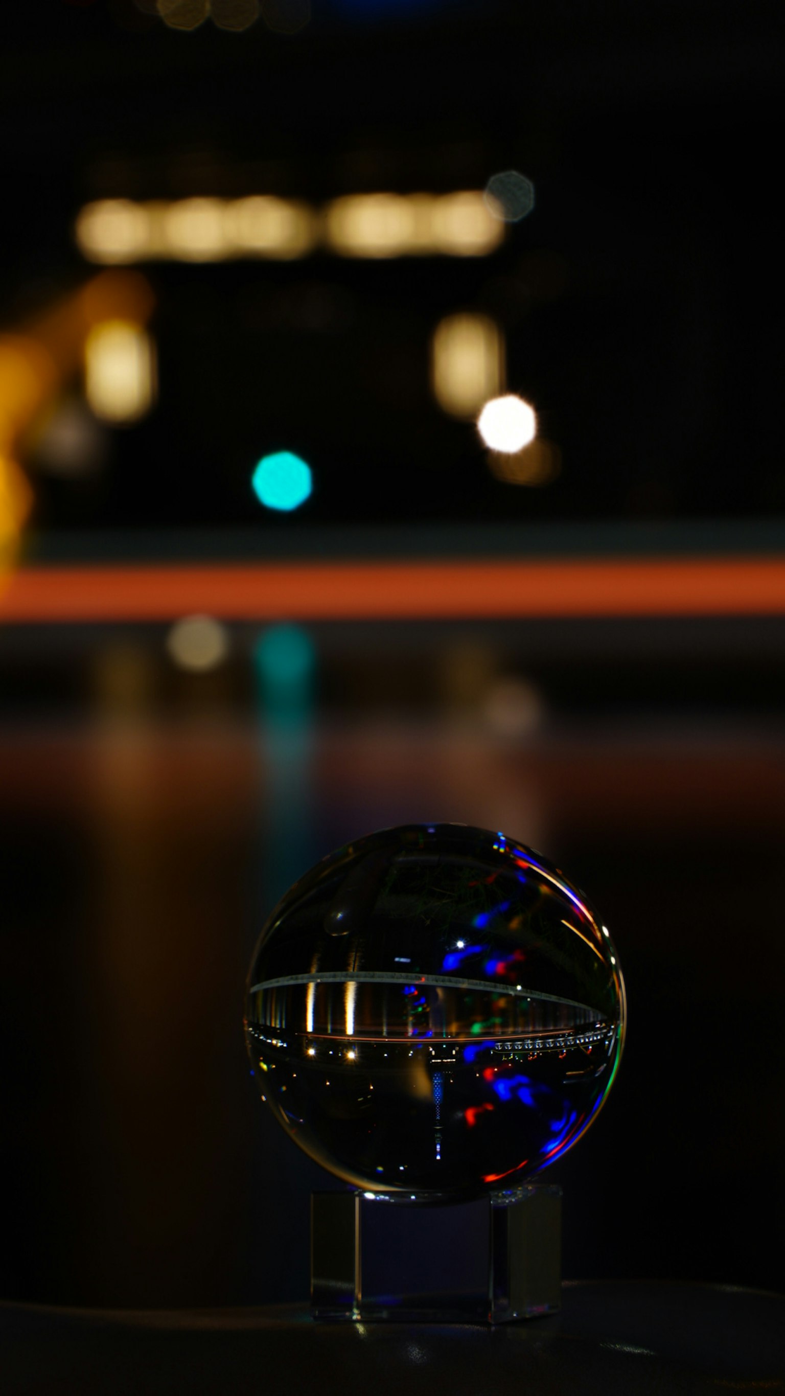 Transparente Kristallkugel, die Stadtlichter mit unscharfem Hintergrund reflektiert