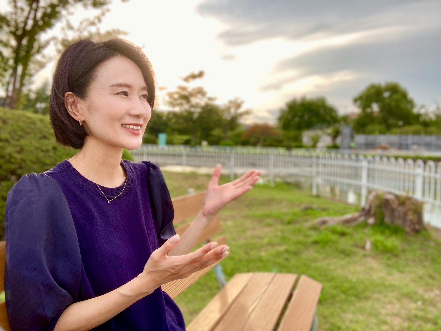 Donna che parla in un parco con uno sfondo di cielo e vegetazione
