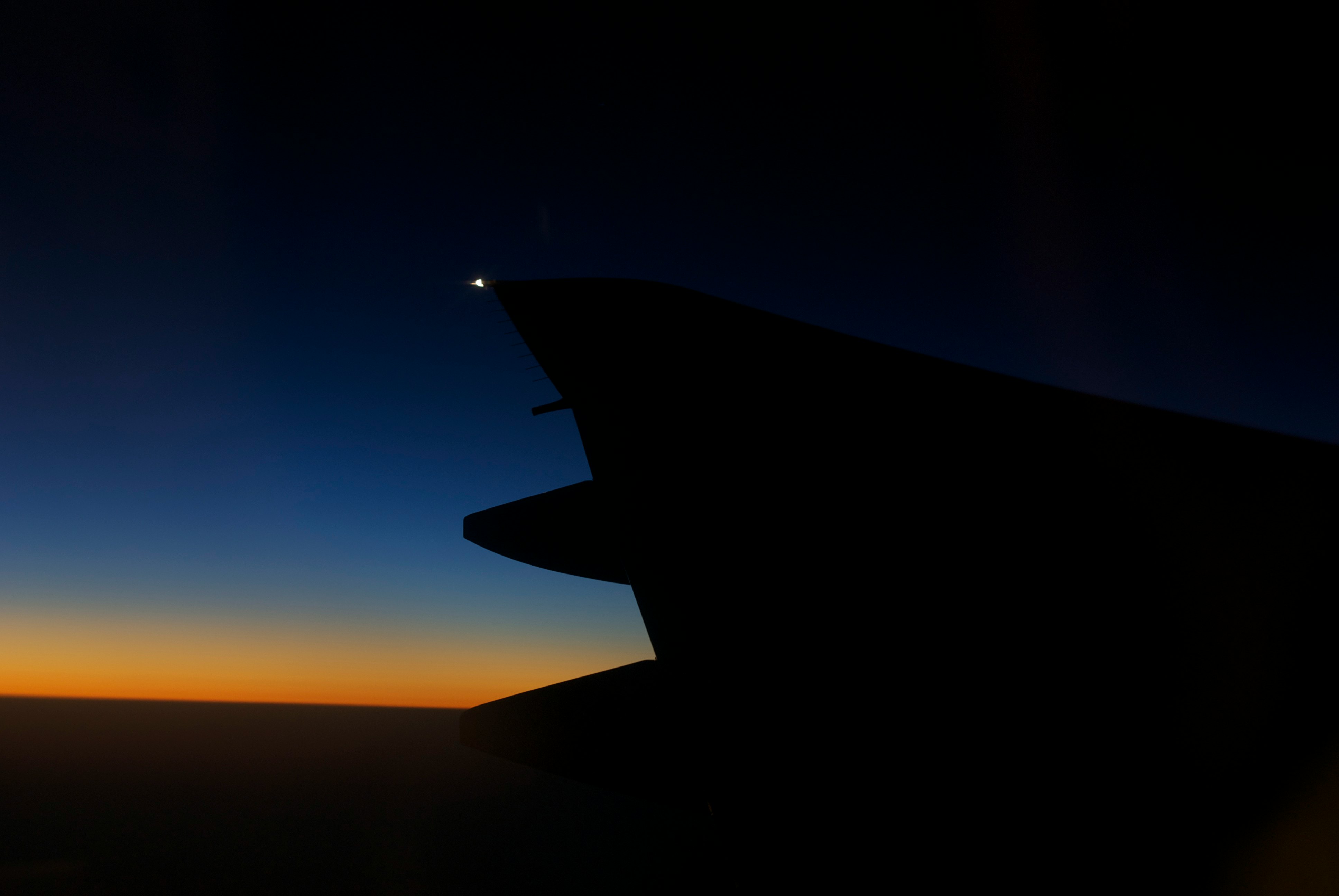 夕暮れの空を背景にした飛行機の翼のシルエット