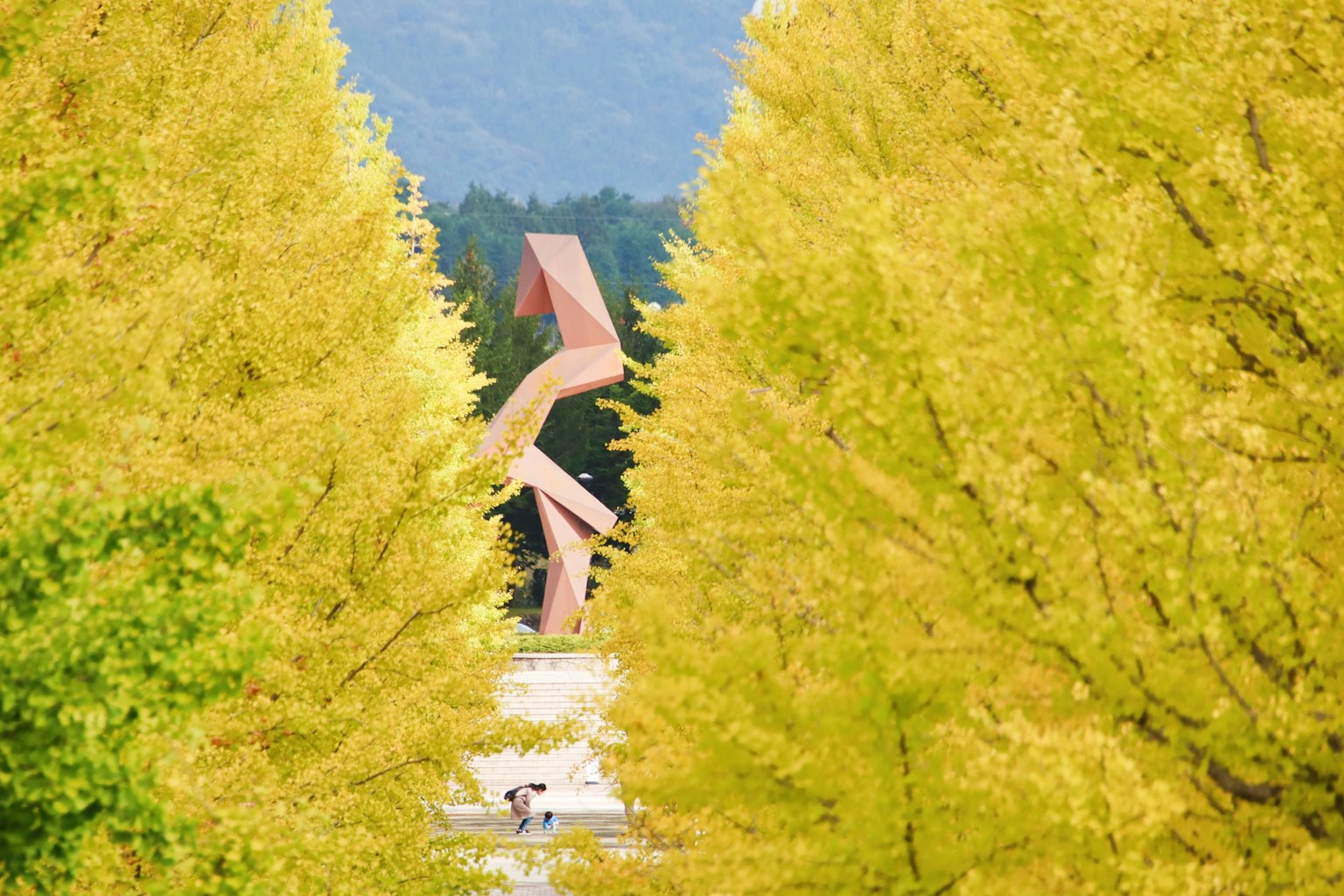 Paesaggio con una scultura incorniciata da alberi di ginkgo gialli