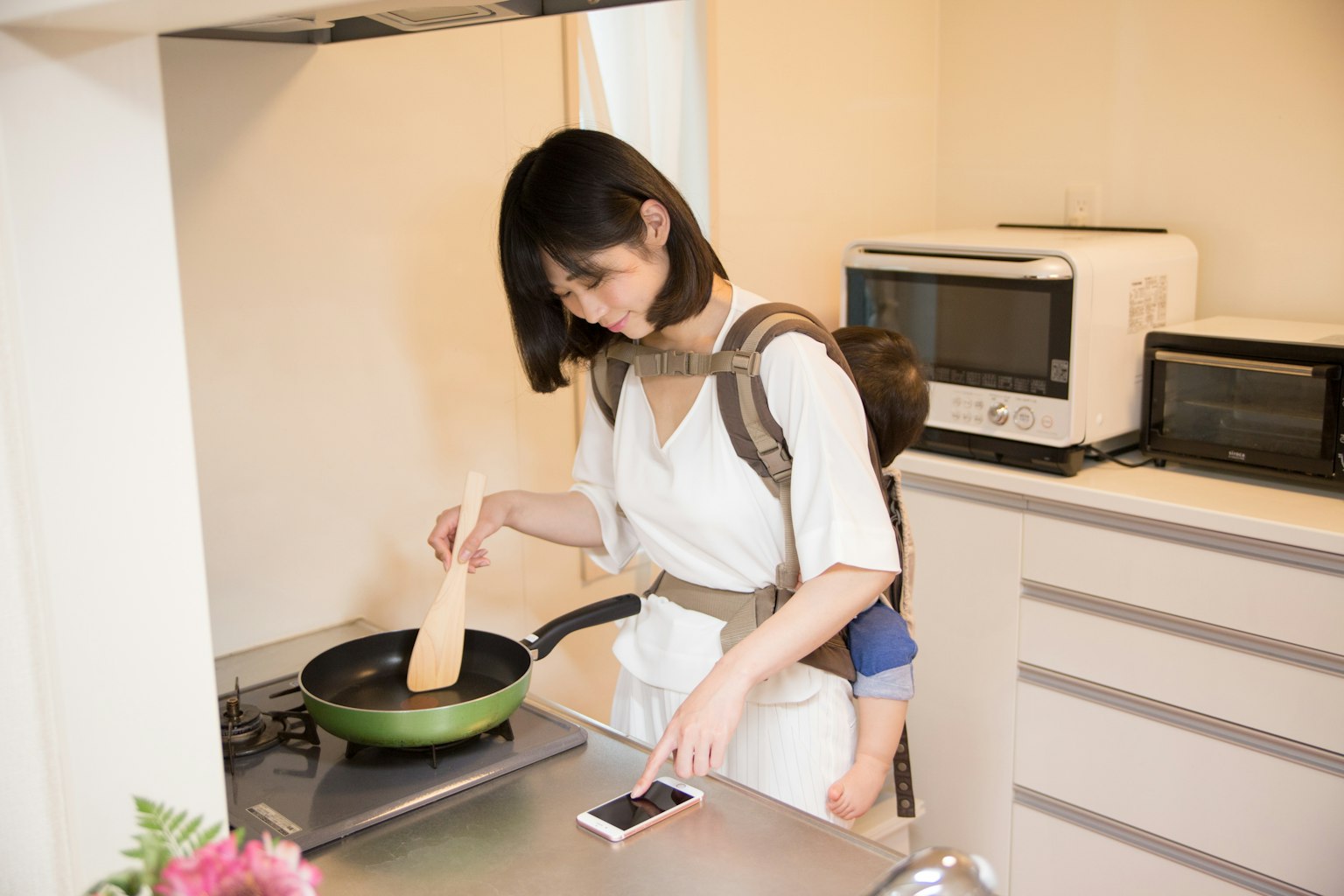 Mère cuisinant dans la cuisine avec un enfant sur le dos