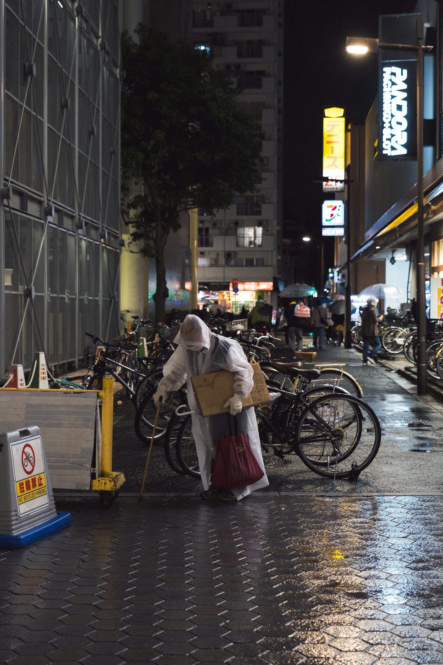 Una persona in abbigliamento bianco in piedi vicino alle biciclette all'angolo di una strada di notte