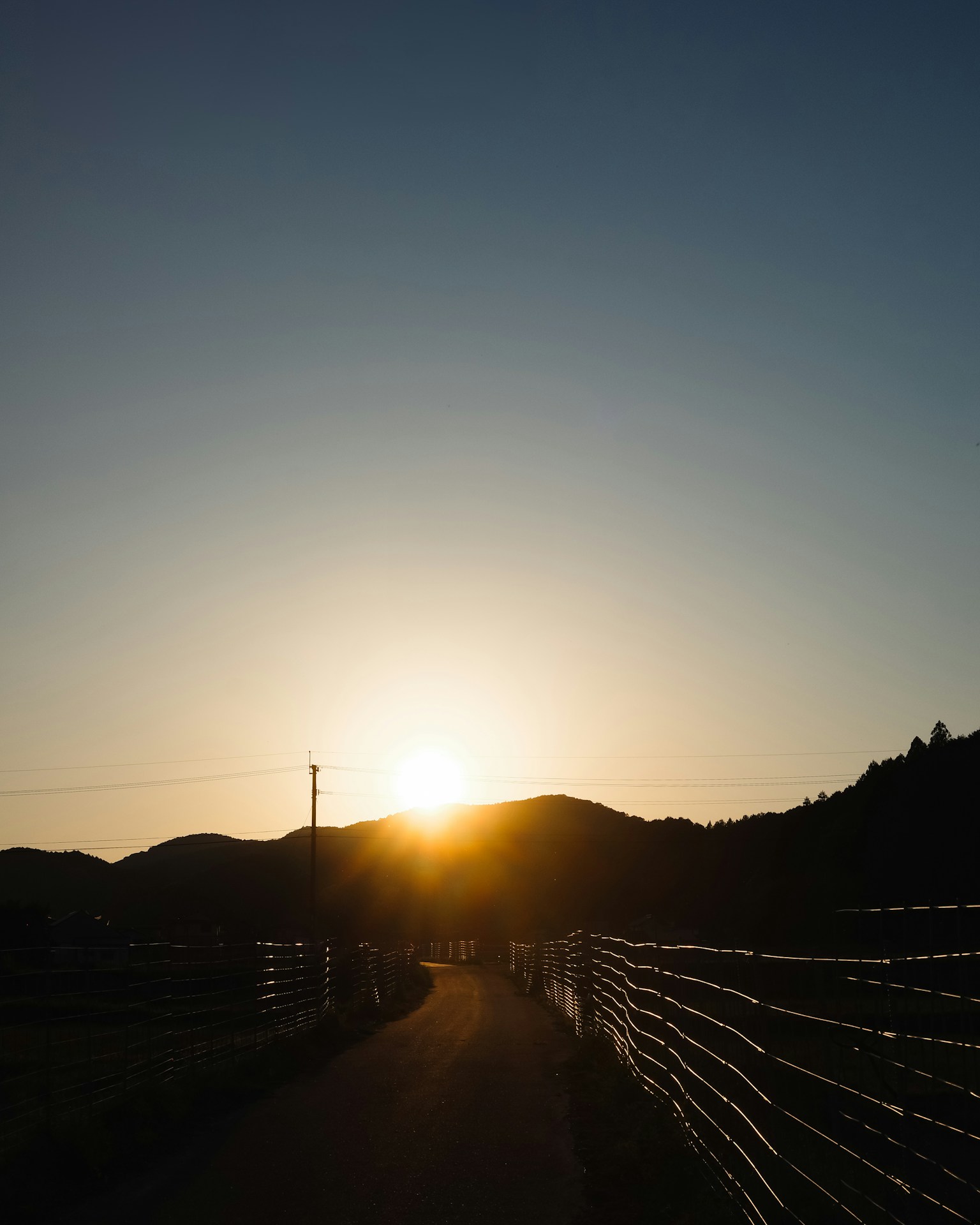 Pathway illuminated by the setting sun with a fence