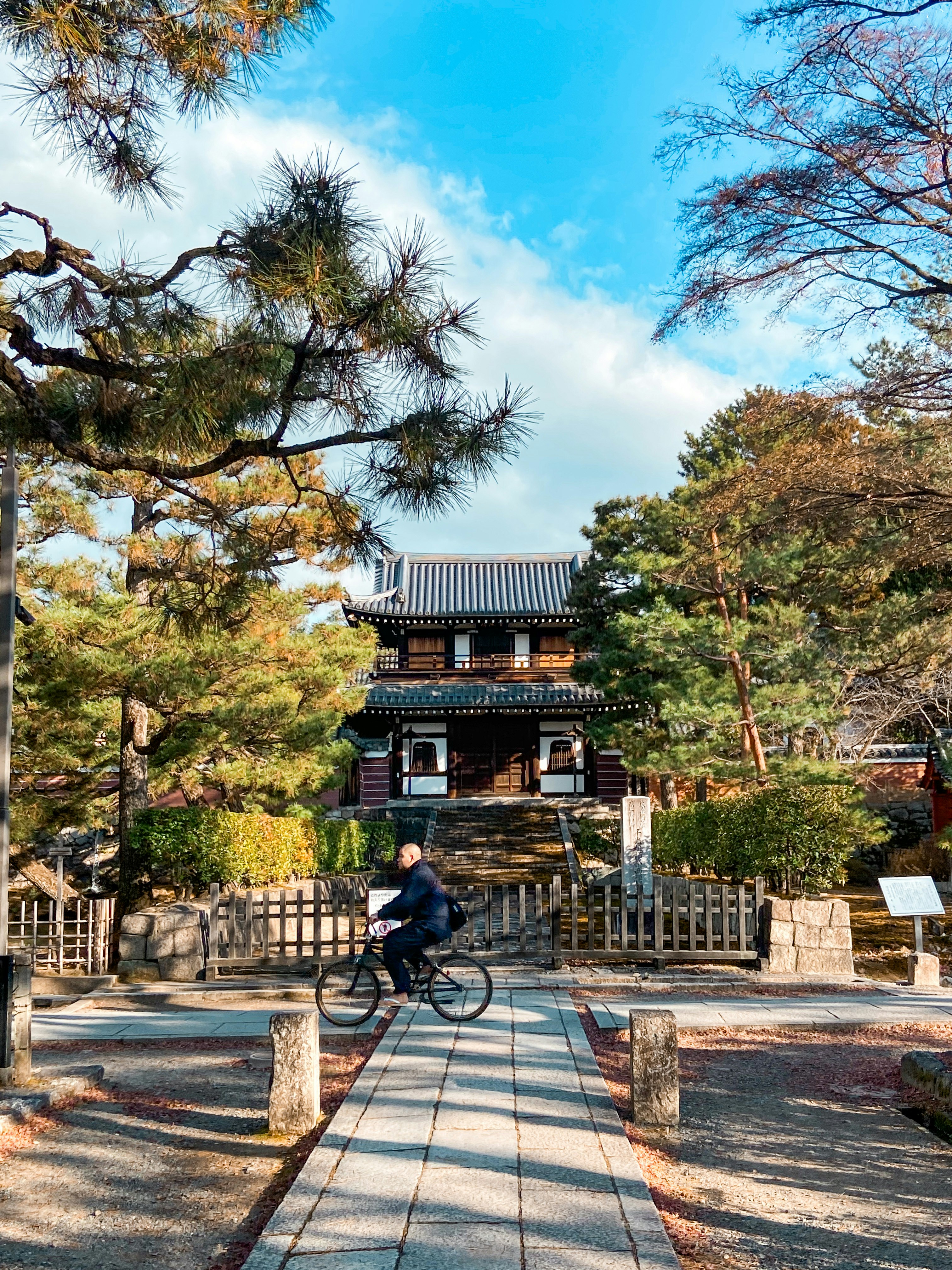 自転車と石畳の参道、紅葉の庭園に囲まれた寺院の門