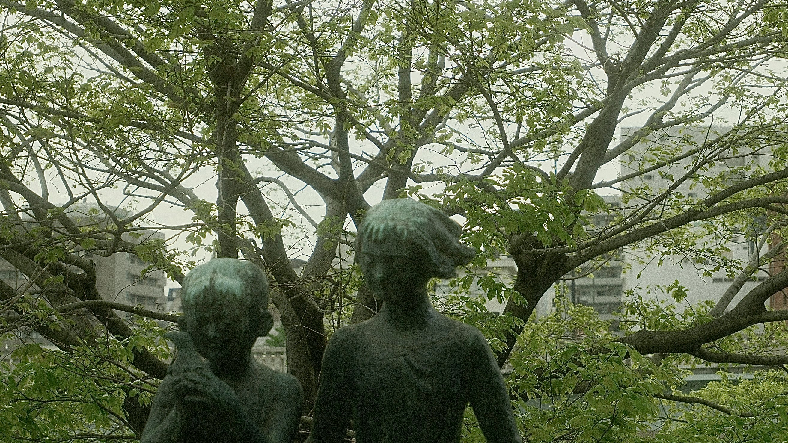 木々の間に並ぶ彫刻像のある庭園の風景