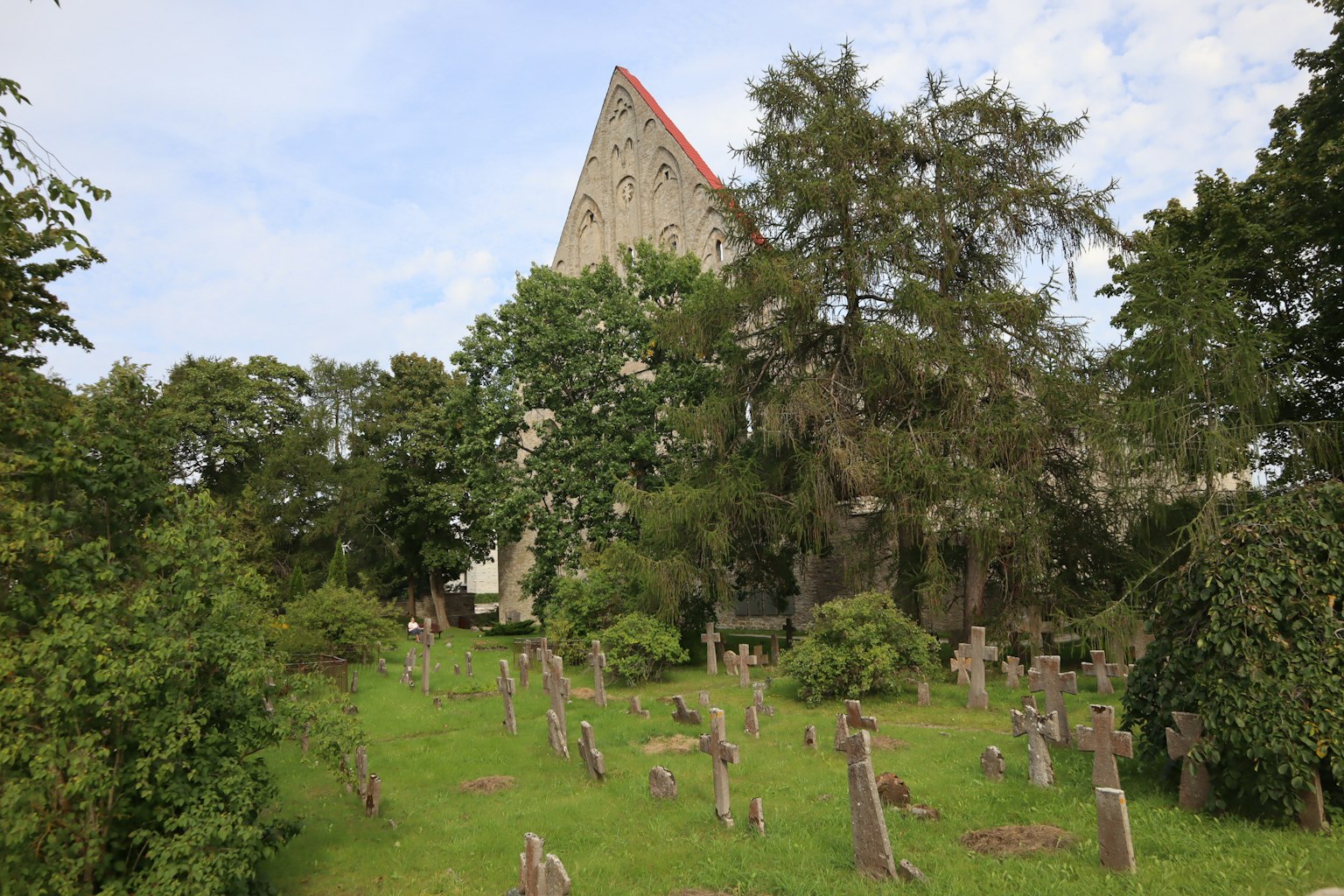 Friedhof mit Grabsteinen, die über grünes Gras in der Nähe einer alten Kirche verstreut sind