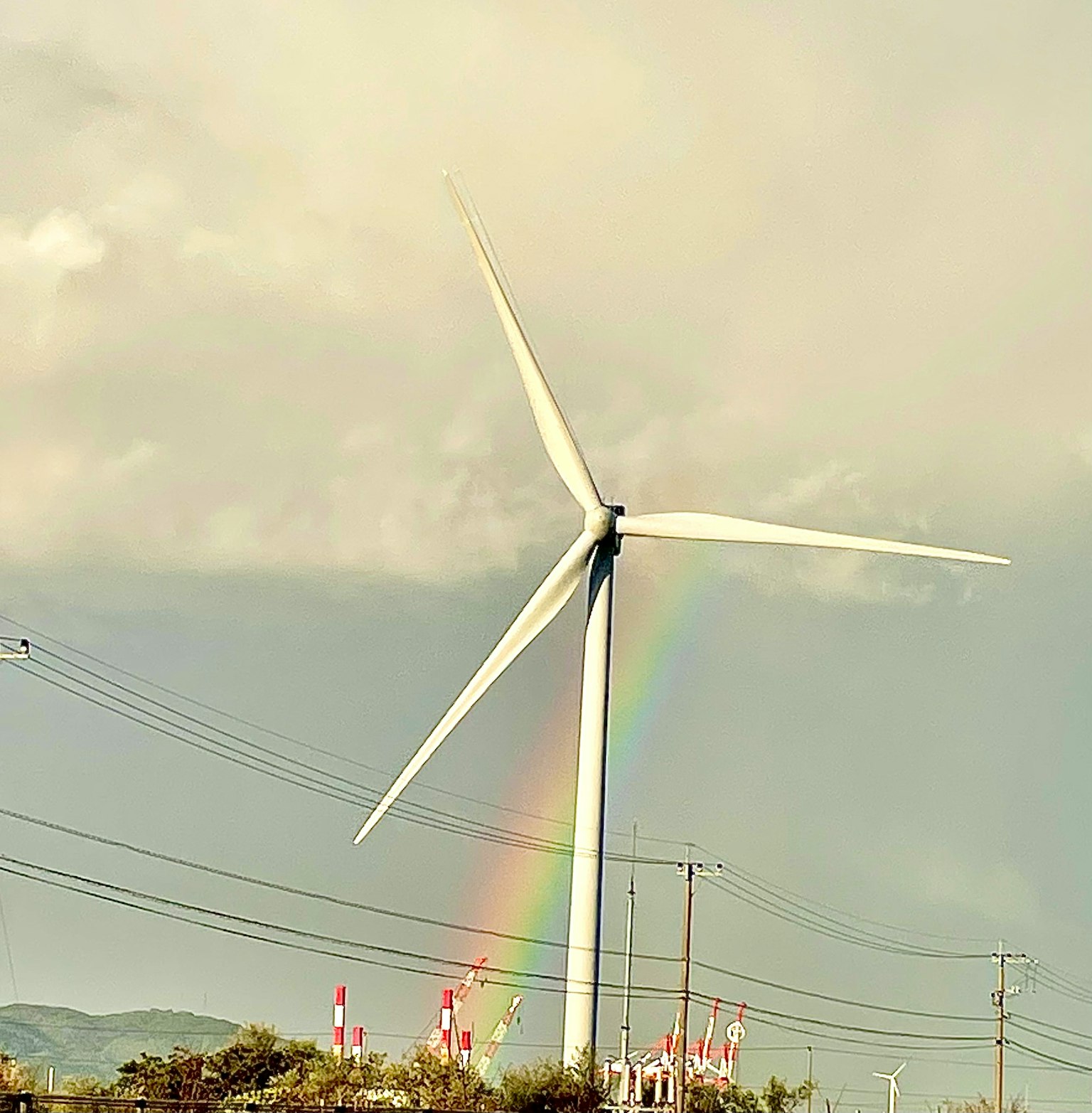 Eine Windkraftanlage mit einem Regenbogen im Hintergrund