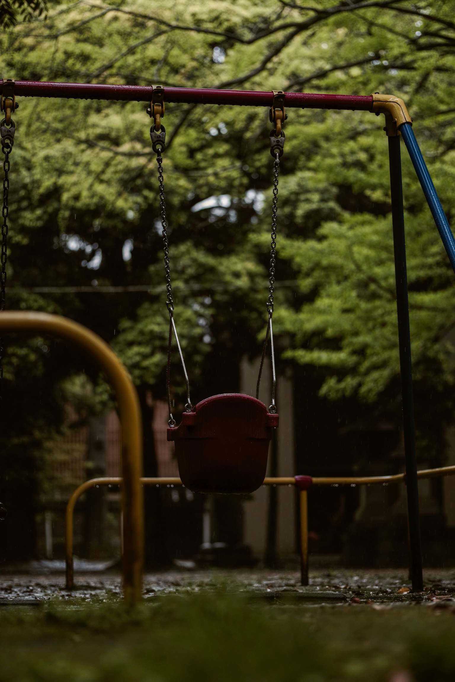 Un columpio en un parque rodeado de árboles verdes