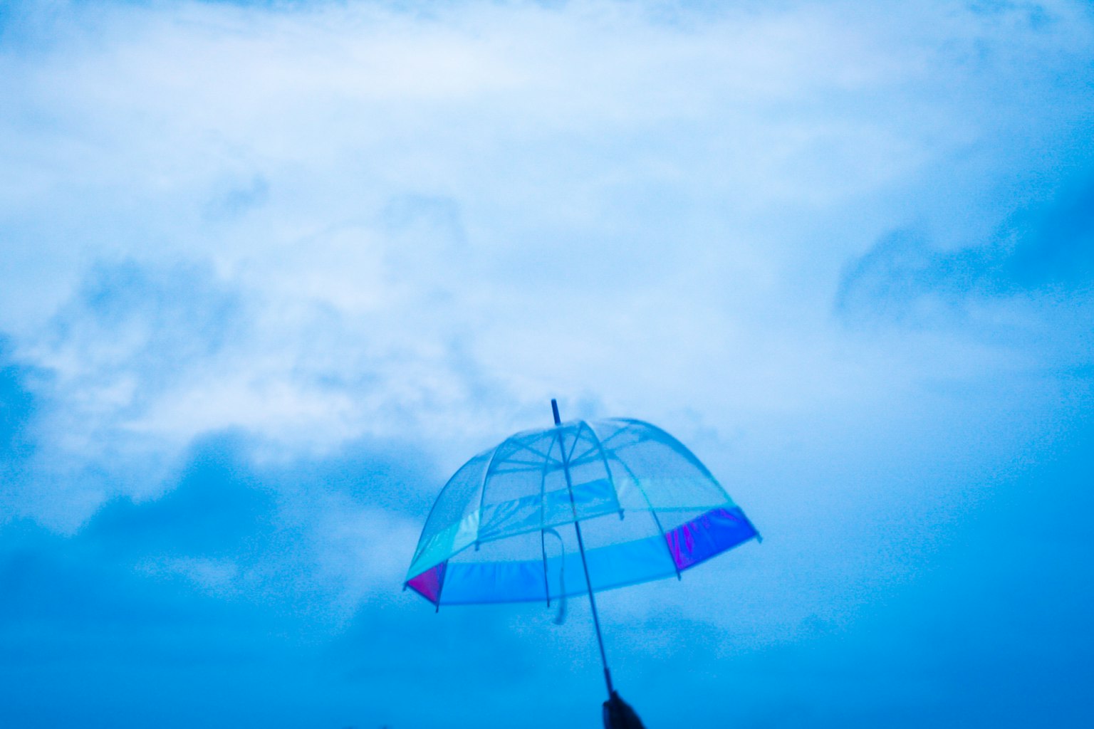 Image of a transparent umbrella held against a blue sky
