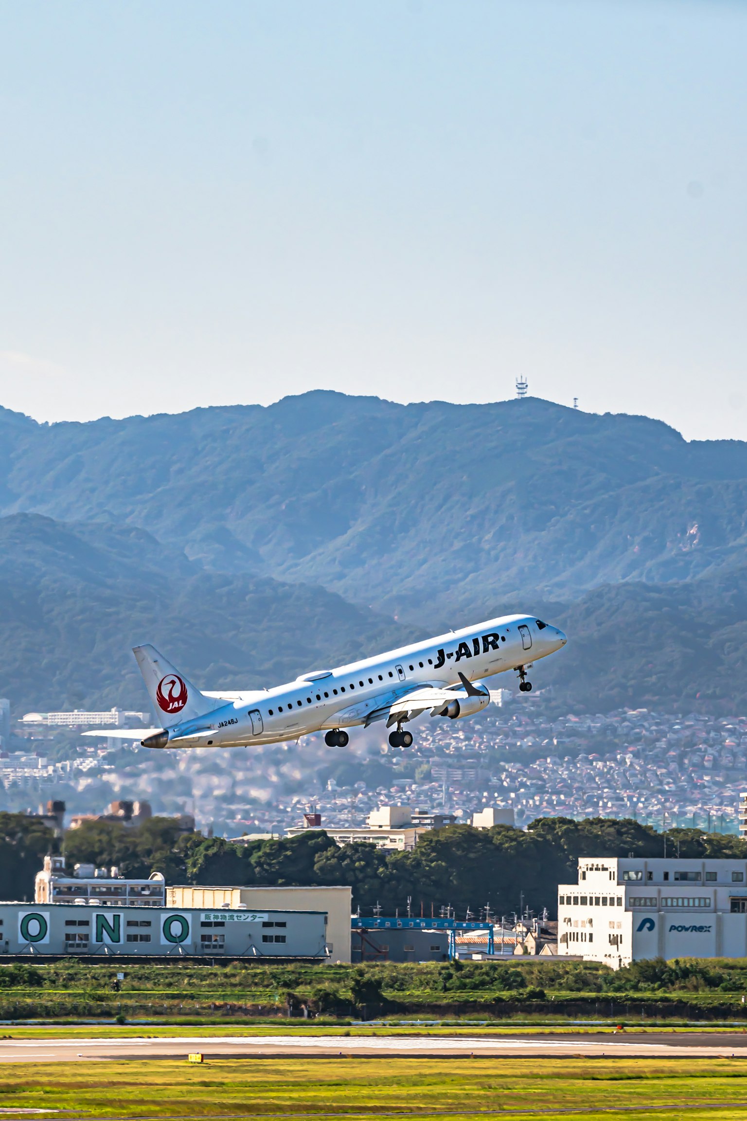 Avion bleu décollant avec des montagnes et une ville en arrière-plan