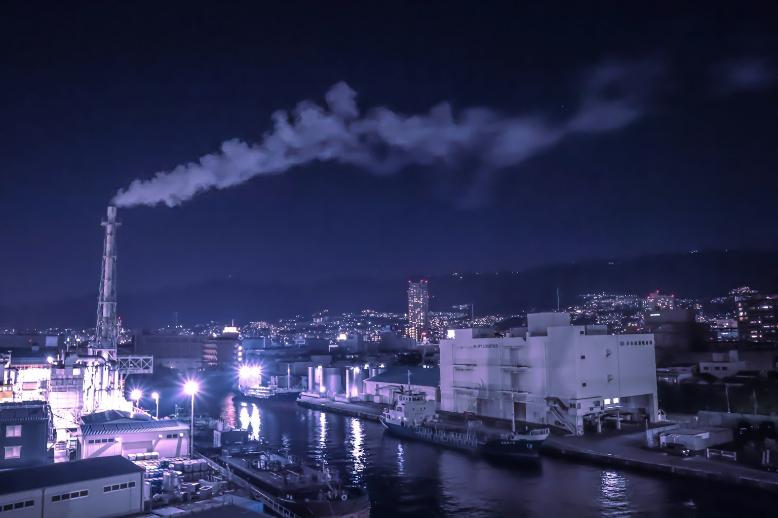 Nachtansicht eines Industriegebiets mit Rauch aus einem Schornstein