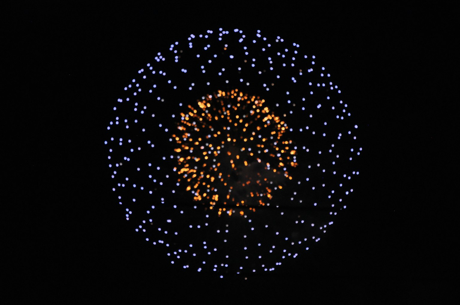 Feuerwerk in Blau und Orange gegen einen schwarzen Himmel
