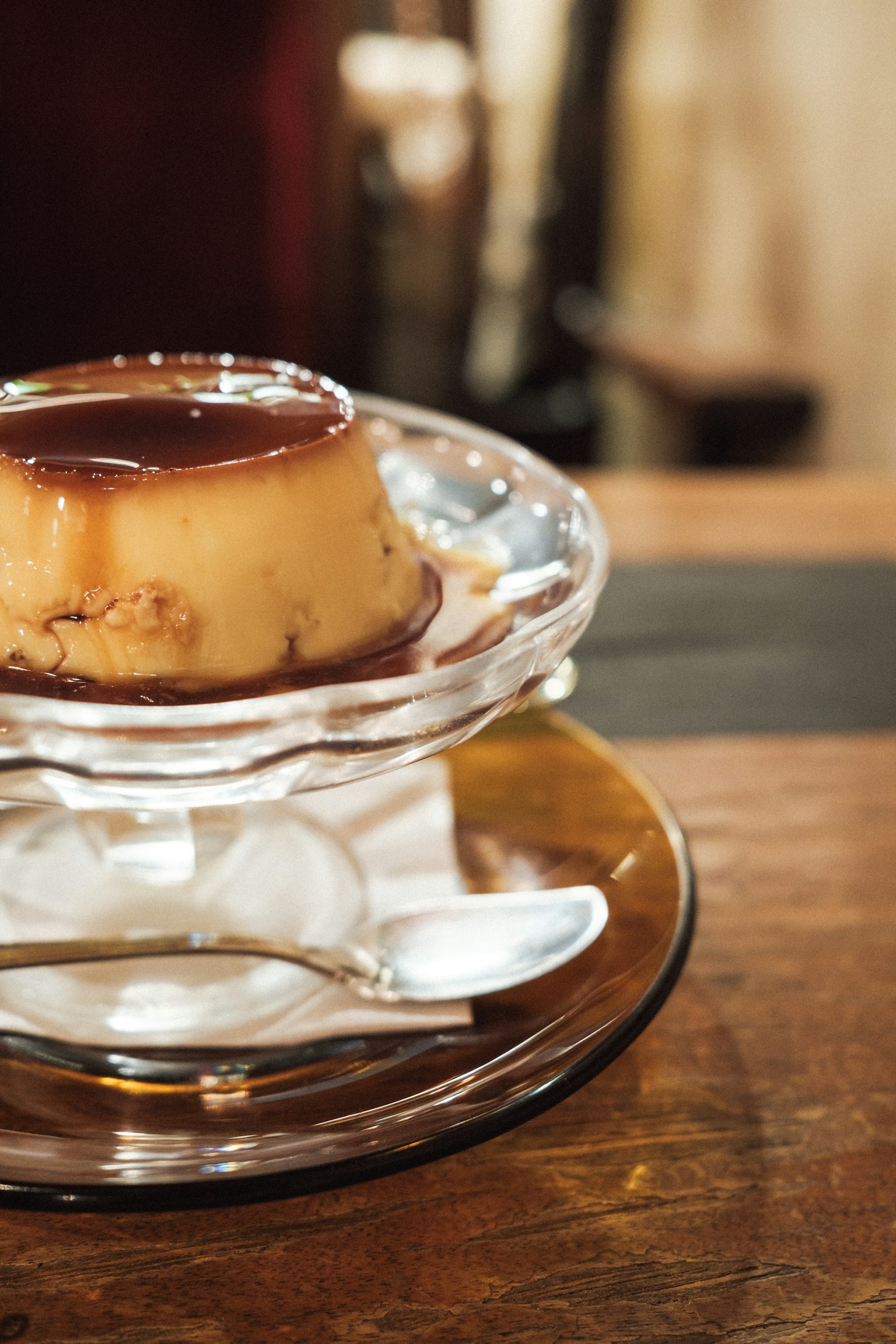 Pudding di crema servito su un piatto trasparente con salsa di caramello