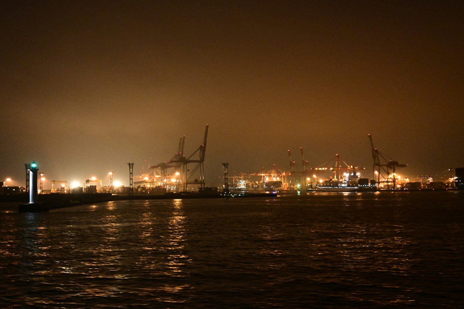Scena portuale notturna con luci scintillanti sull'acqua e gru visibili