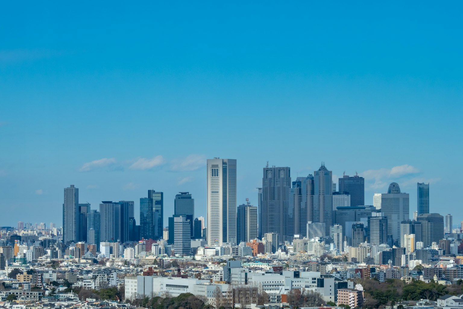 City skyline under blue sky featuring tall buildings and urban landscape