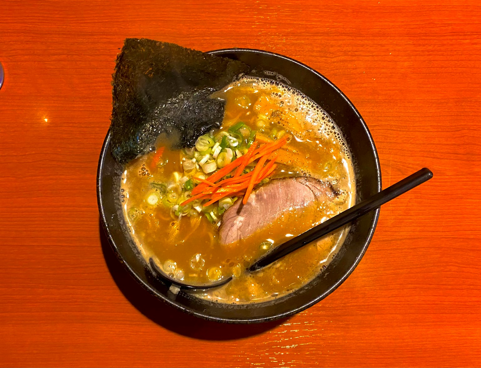 Mangkok ramen dengan irisan chashu dan daun bawang dalam kaldu