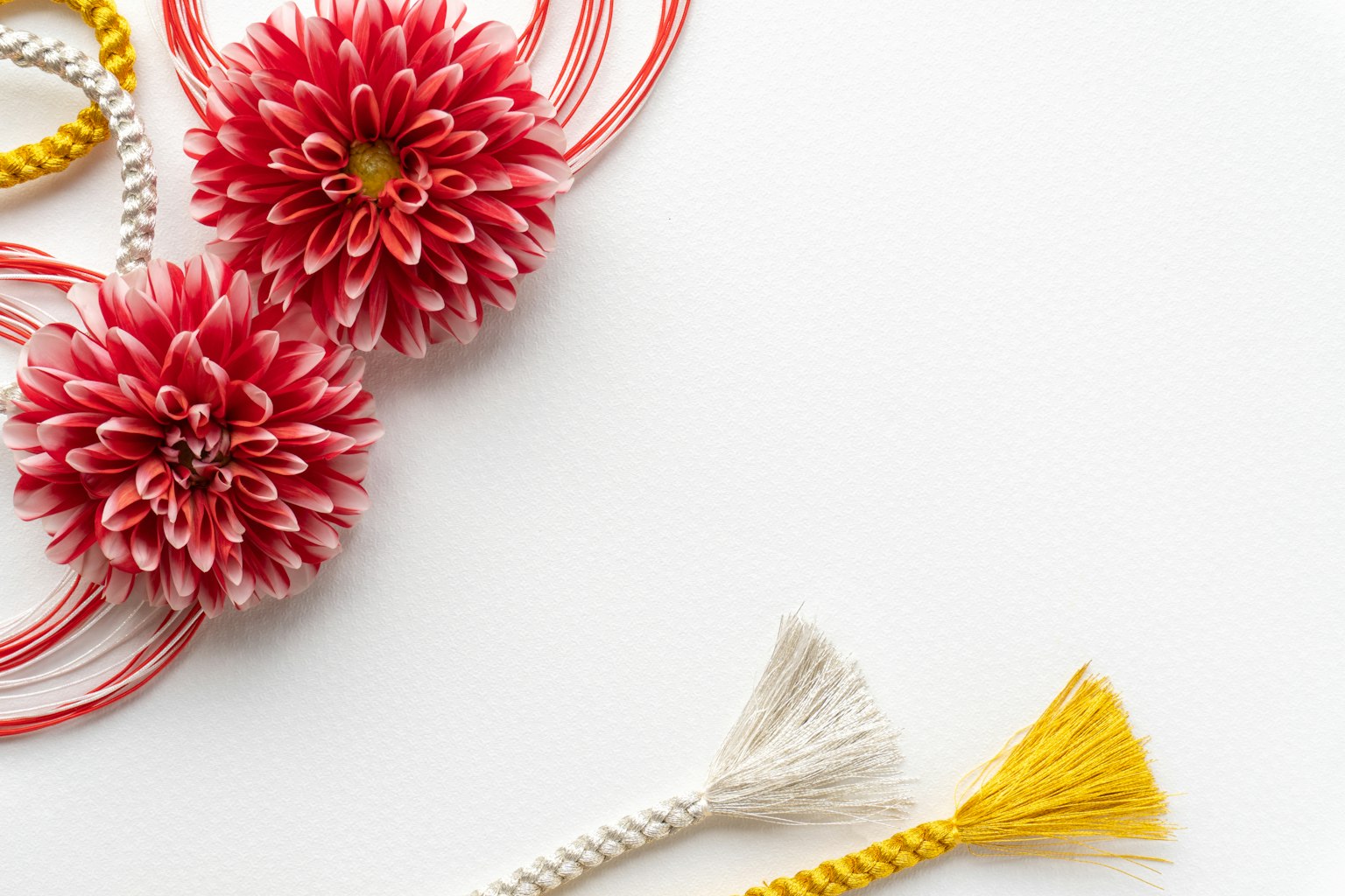 Dekorasi bunga merah dengan tassel putih dan kuning di latar belakang polos