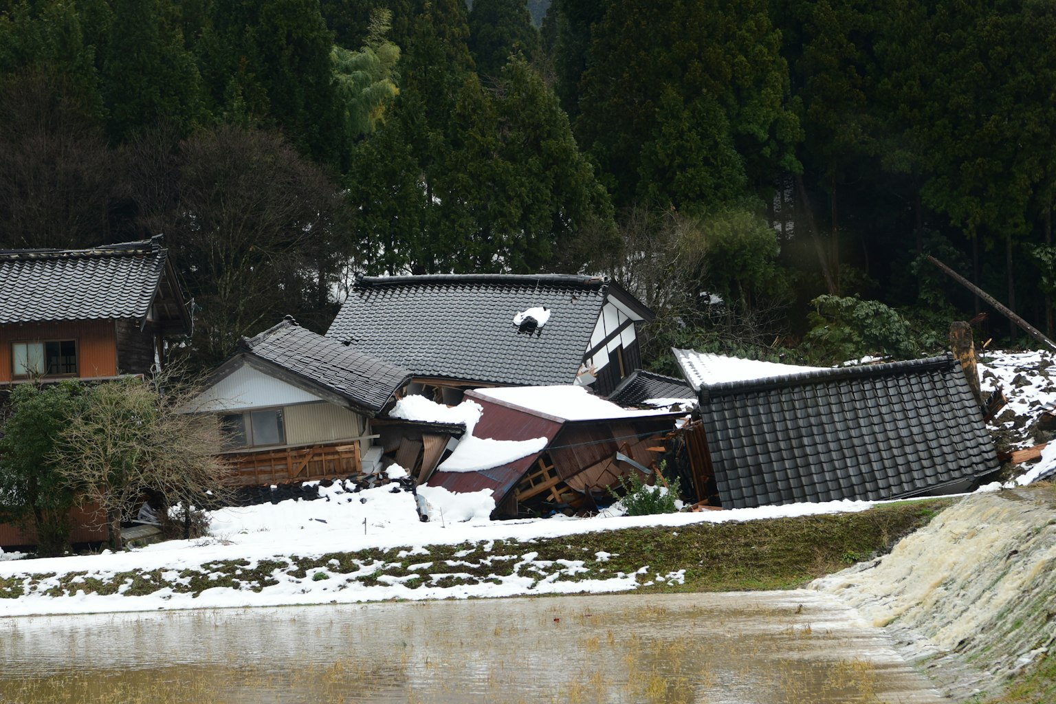 Ländliche Szene mit eingestürzten Häusern, die mit Schnee bedeckt sind