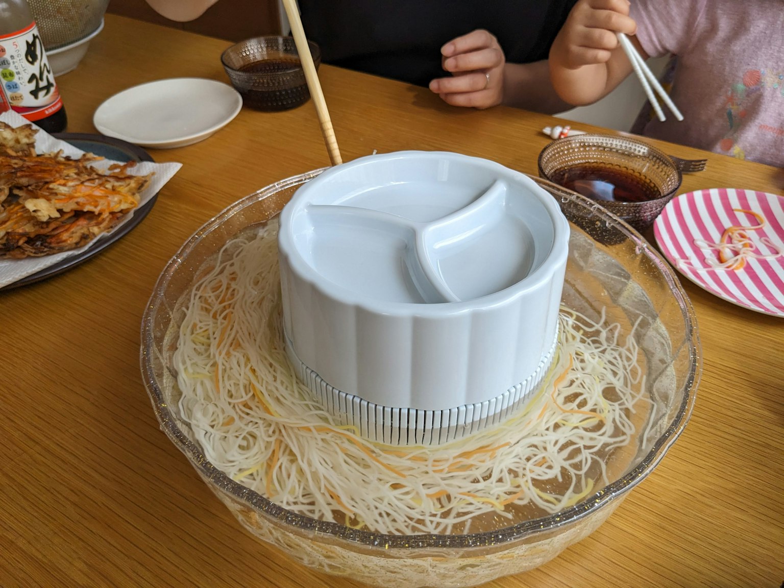 Plat blanc avec des nouilles somen et des baguettes sur une table avec divers plats