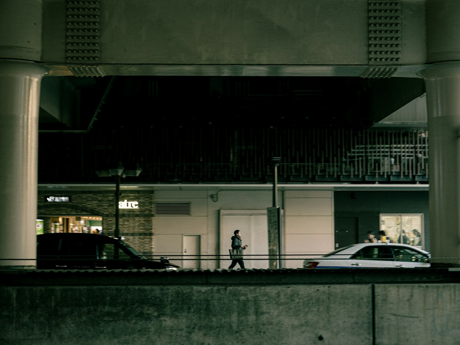 Urban scene with a person walking and cars on a dark street