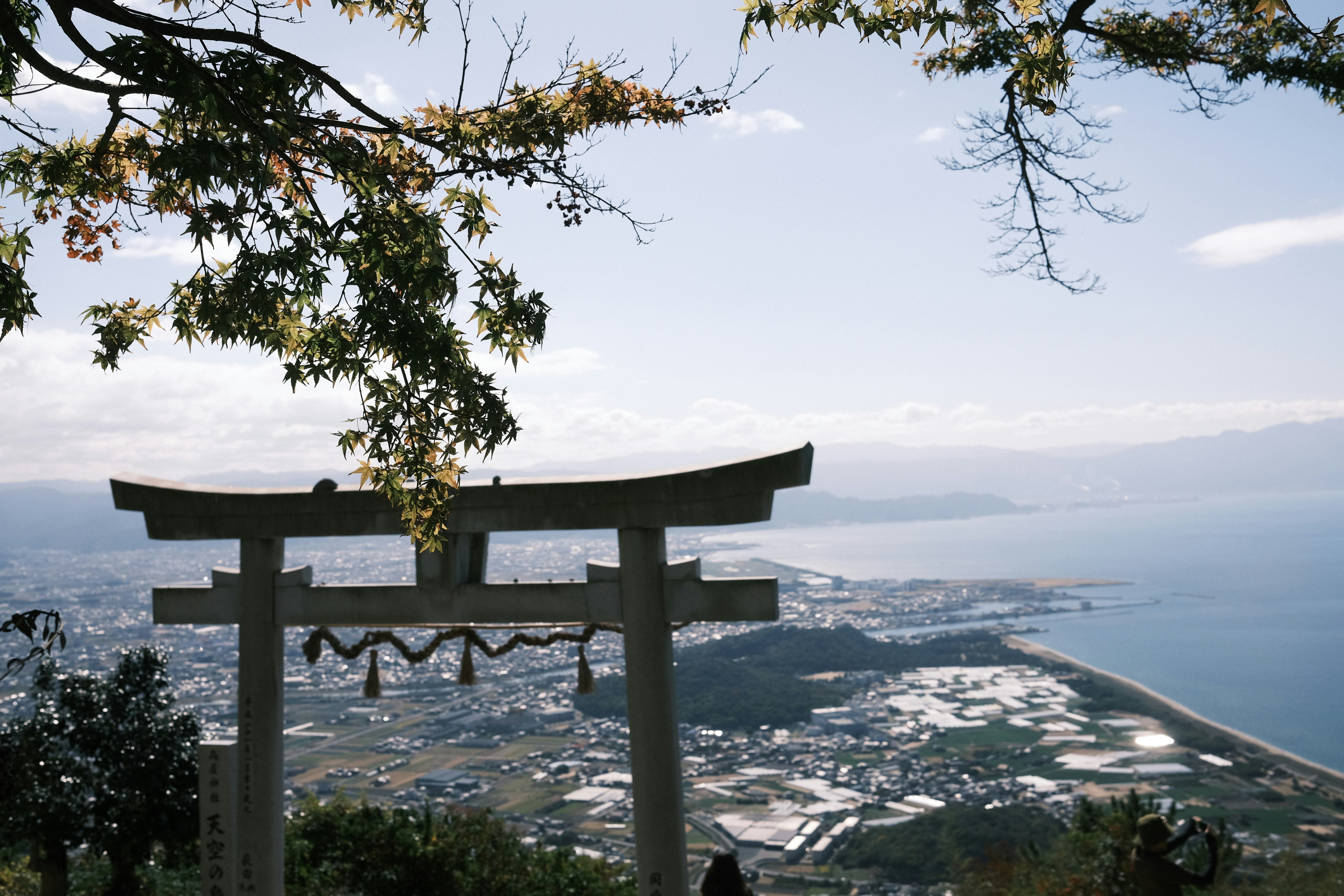Silhouette of a torii gate with a beautiful view of the ocean from a mountain