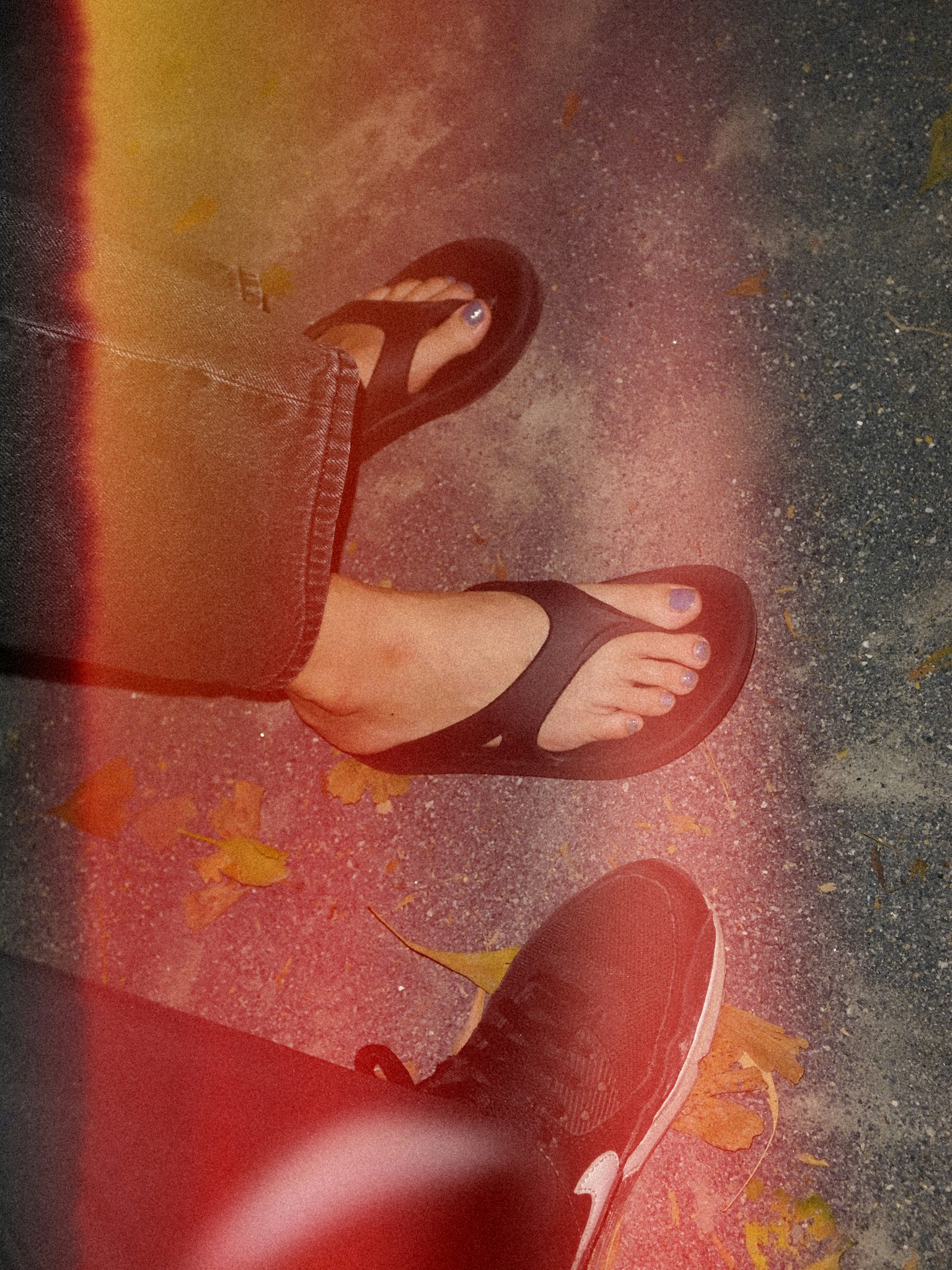 Close-up of feet wearing flip-flops and sneakers with colorful filter effect