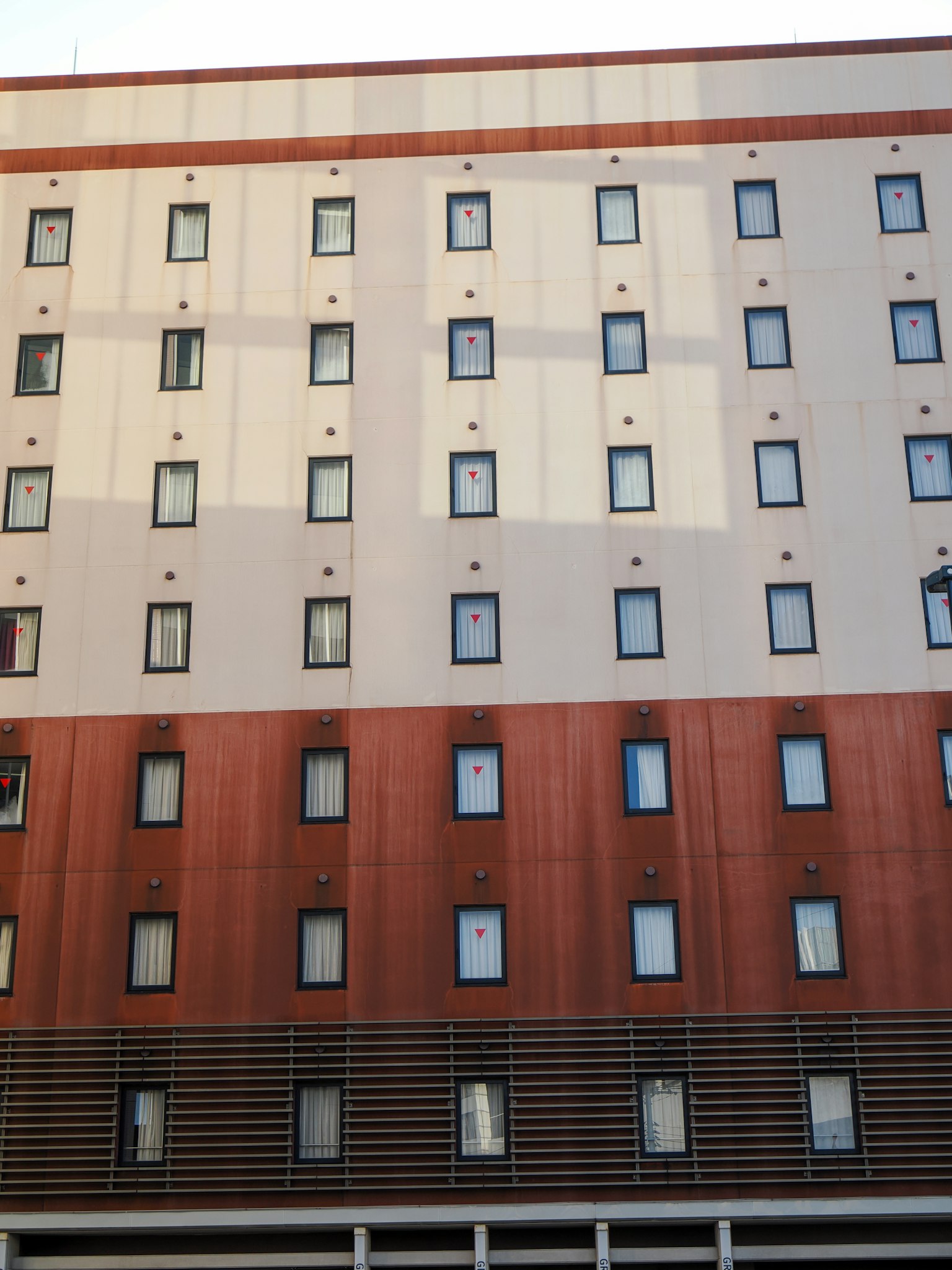 Une façade de bâtiment avec un motif de couleurs marron et crème comportant des fenêtres régulièrement espacées