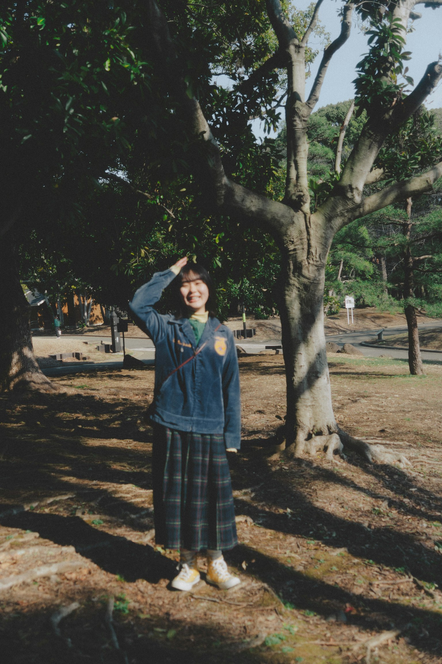 穿着蓝色夹克的女人在树下摆姿势