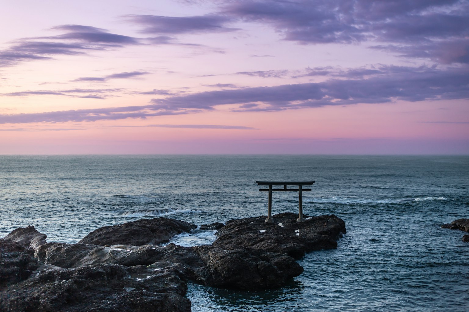 Vista panoramica di un torii su una costa rocciosa al tramonto con cielo colorato