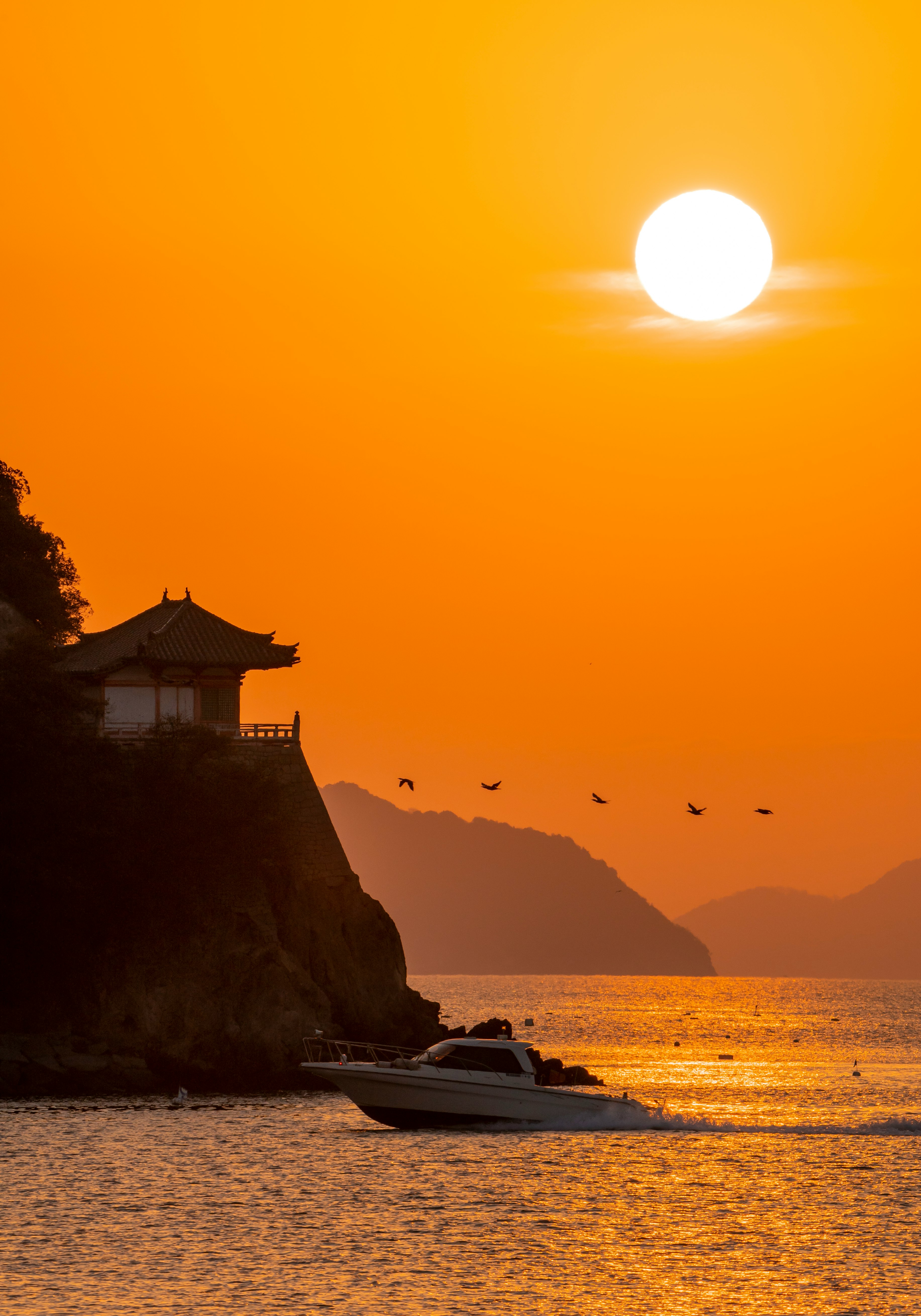 Sunset seascape with a boat near a cliff