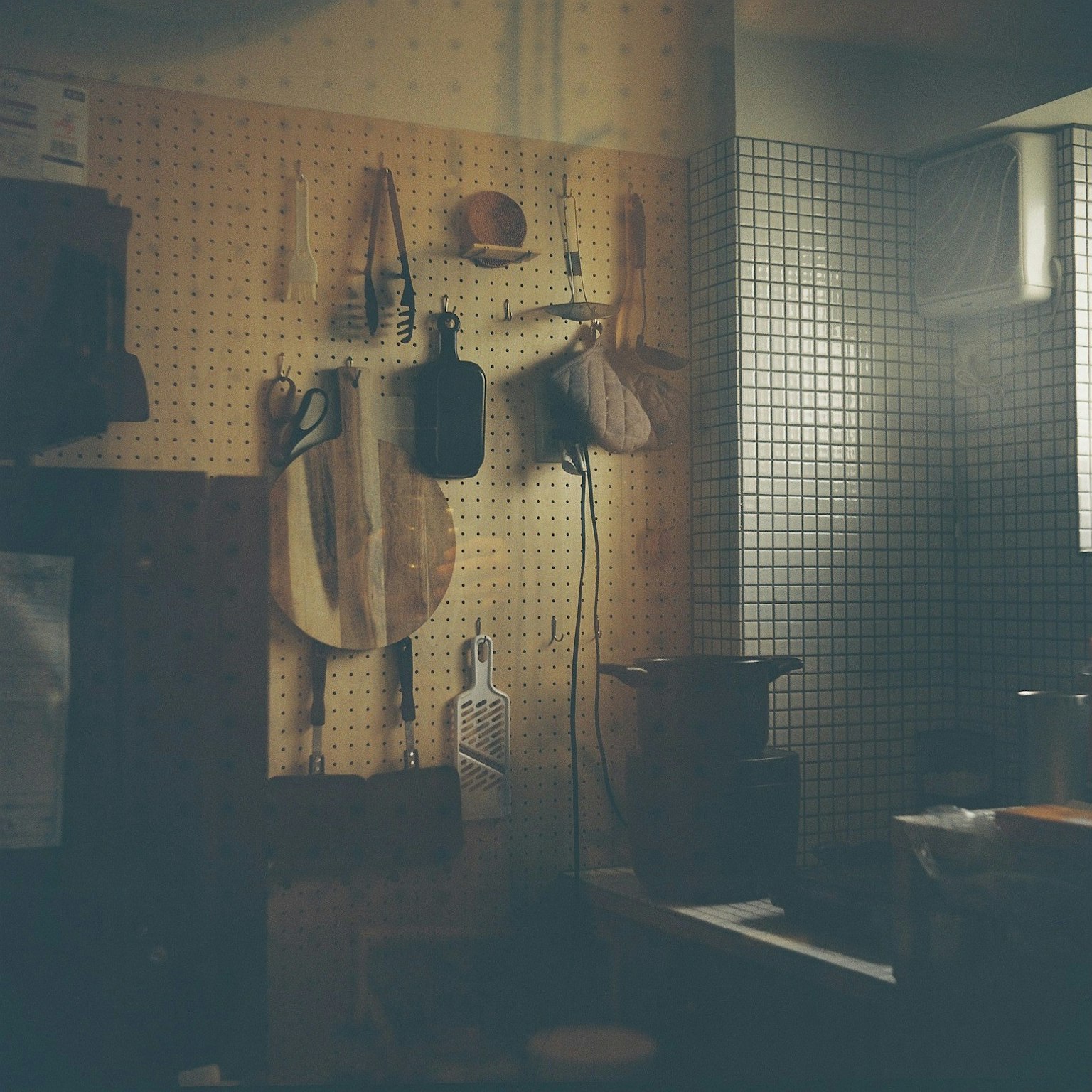 キッチンの壁に掛けられた調理器具と木製のまな板が見える