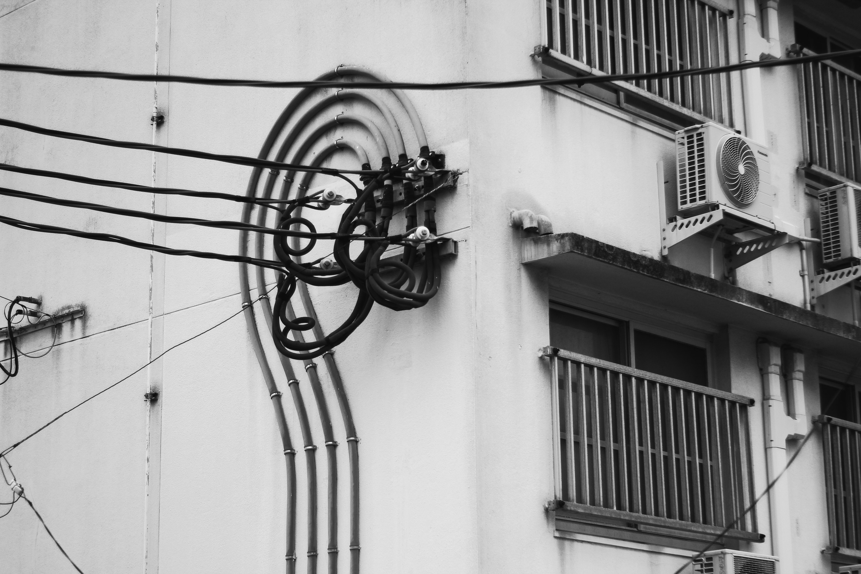 配線と配管が走る白い建物の外壁