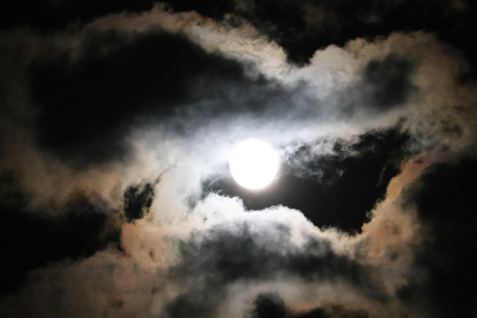 Bulan terang dikelilingi awan gelap di langit malam