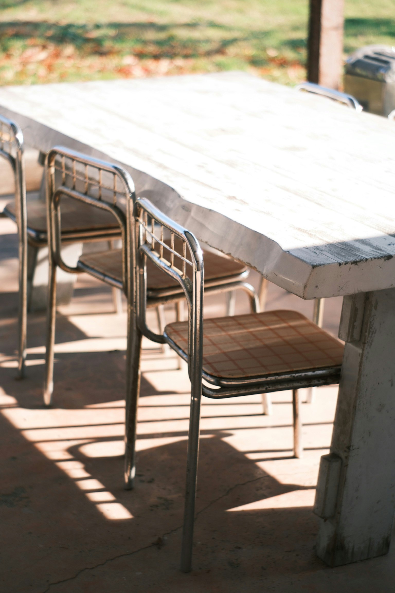 白いテーブルと金属製の椅子が並ぶ屋外のダイニングエリア