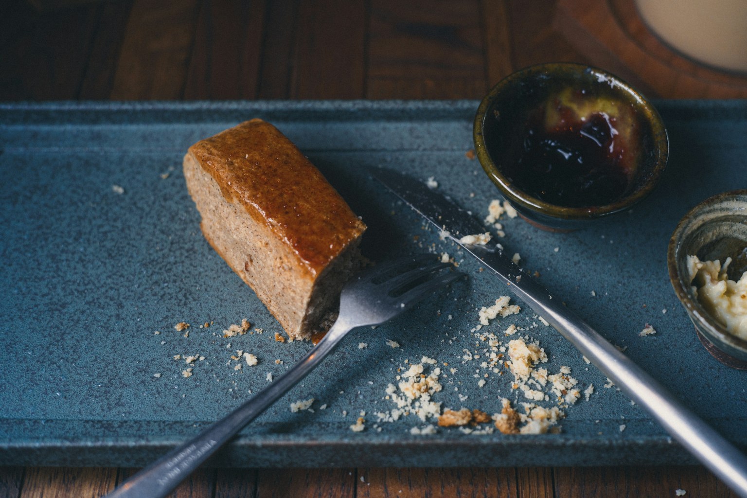 A piece of dessert on a blue plate with a fork and knife beside it