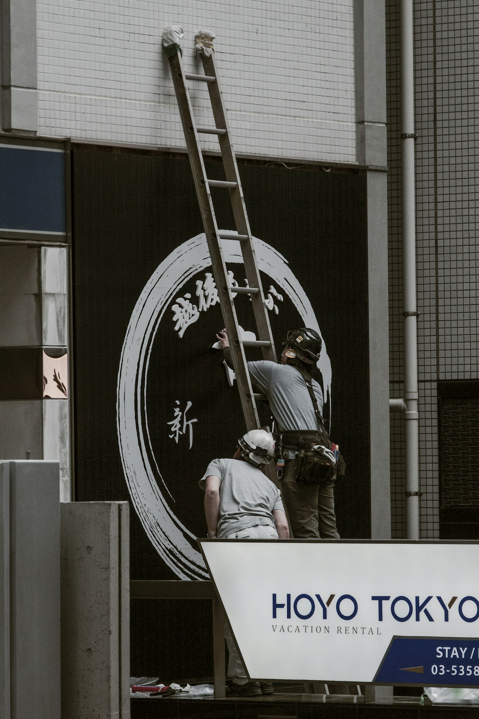 Arbeiter reparieren ein Schild in Tokio mit einer Leiter