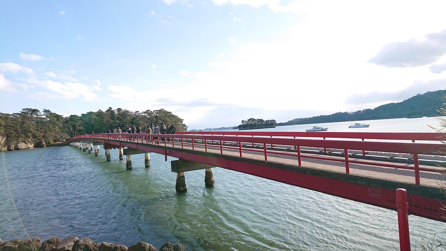 红色桥梁横跨水面，周围是自然风光
